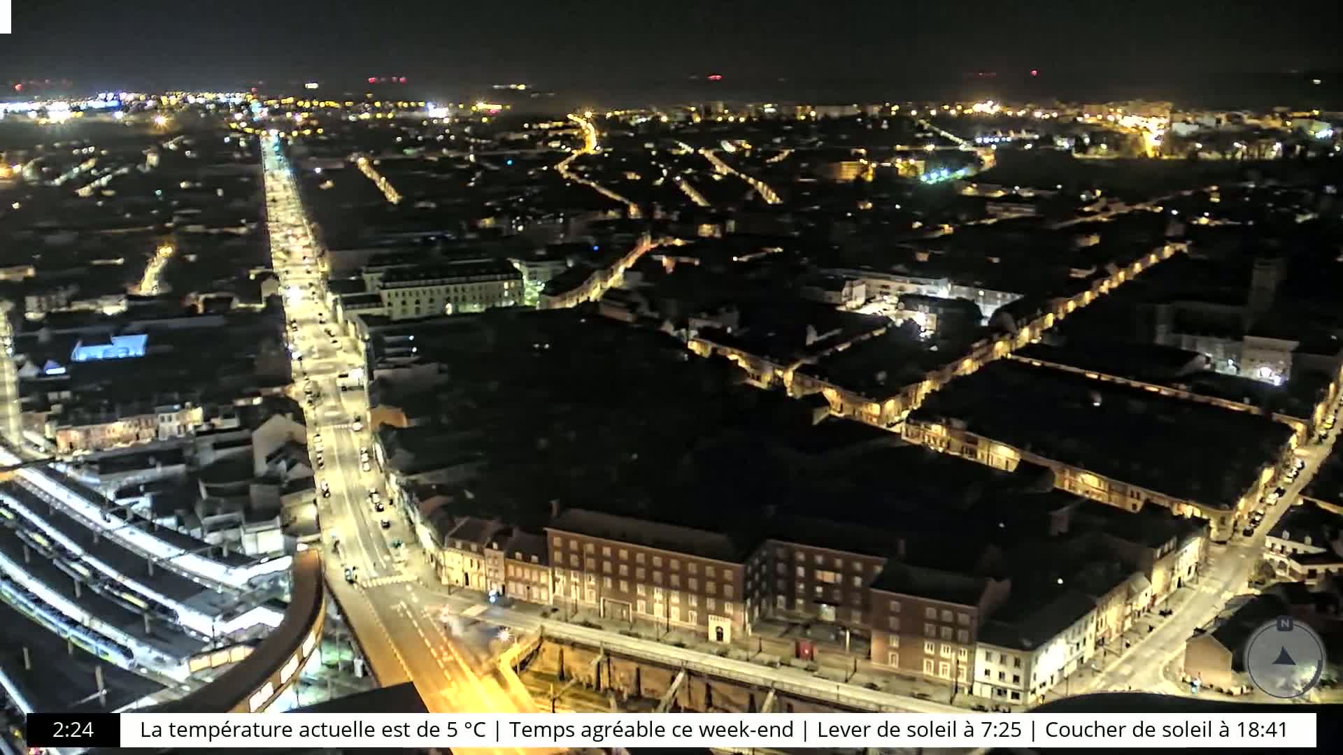 A nighttime aerial view of a city with illuminated streets and buildings.