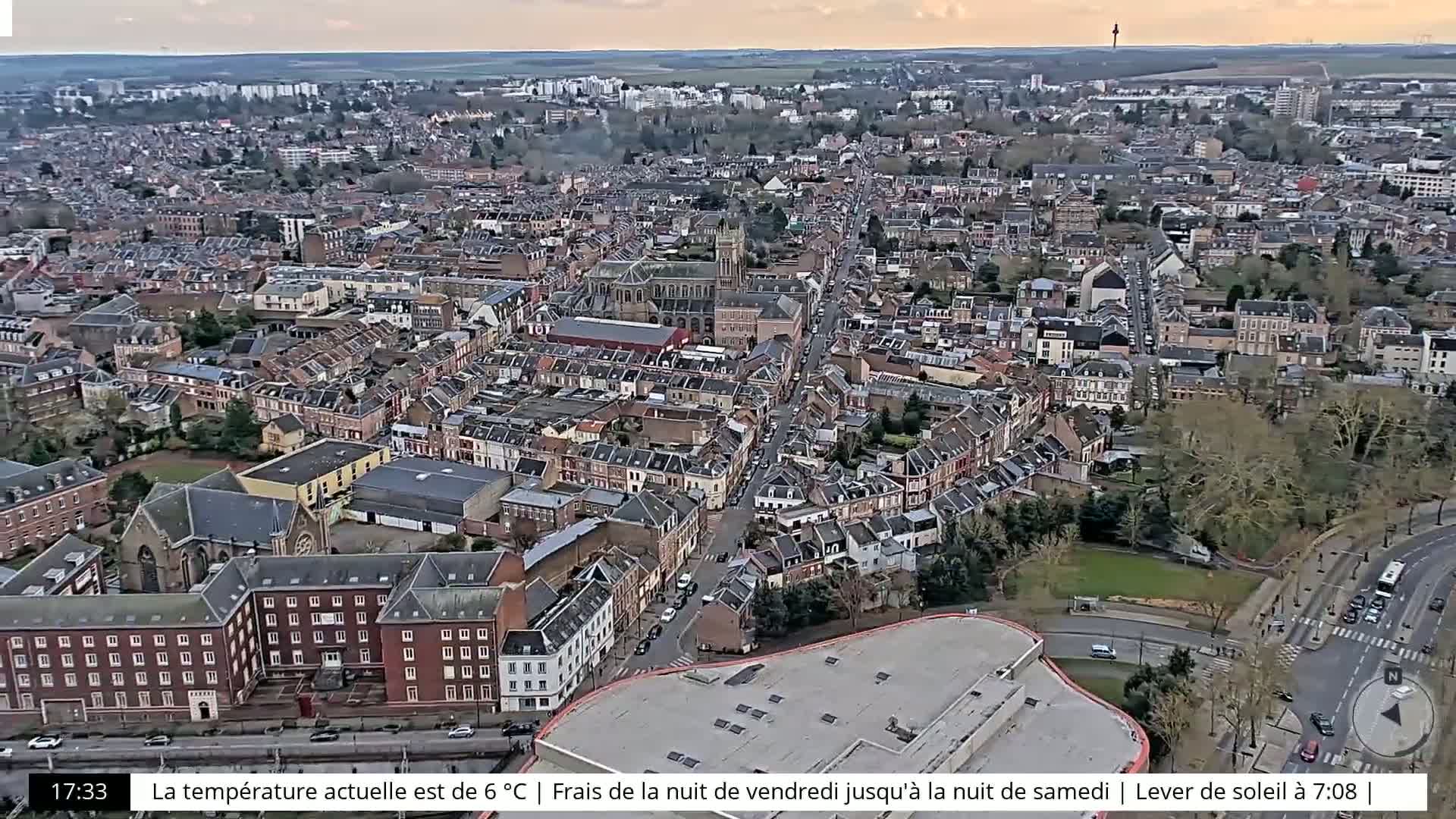 An aerial view shows a densely populated European town under a partly cloudy sky.