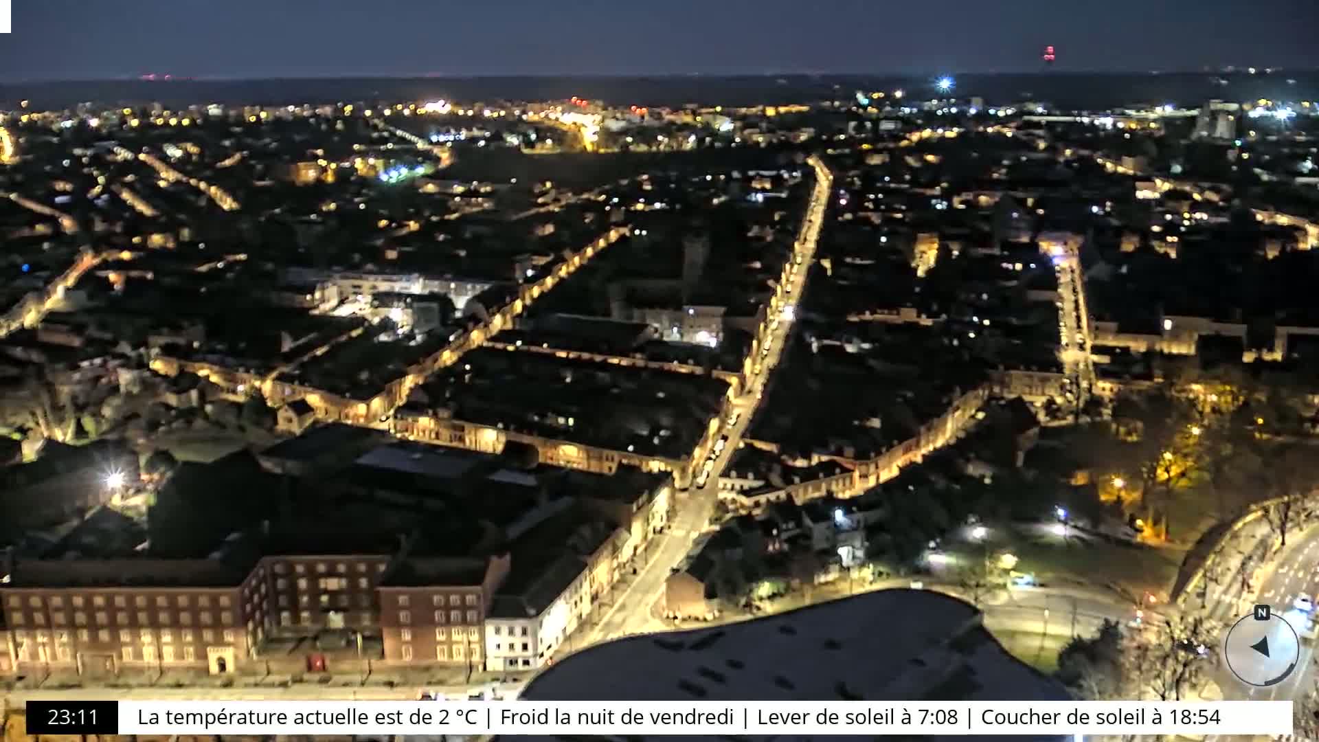 A nighttime aerial view of a city with dimly lit streets and buildings under a clear, dark sky.