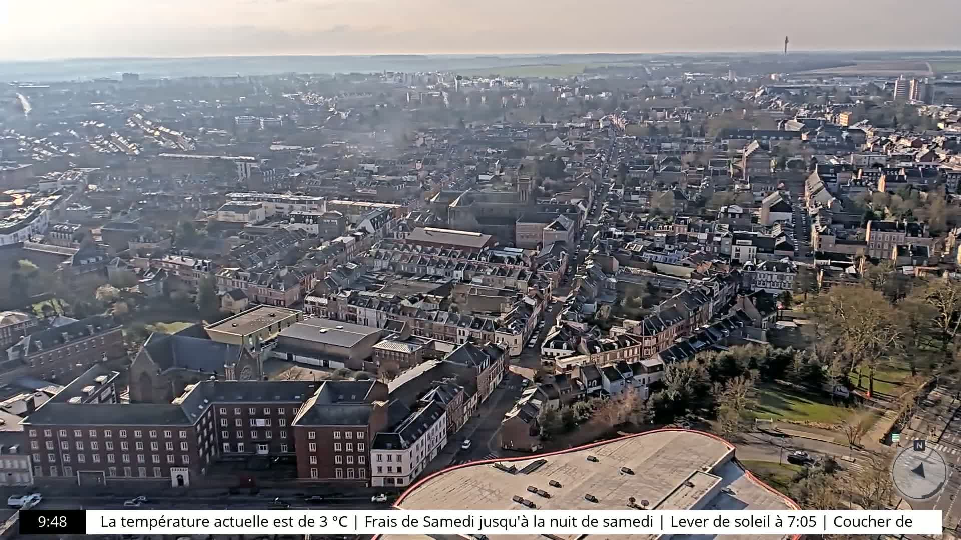 A high-angle, long shot shows a sprawling city on a sunny day.