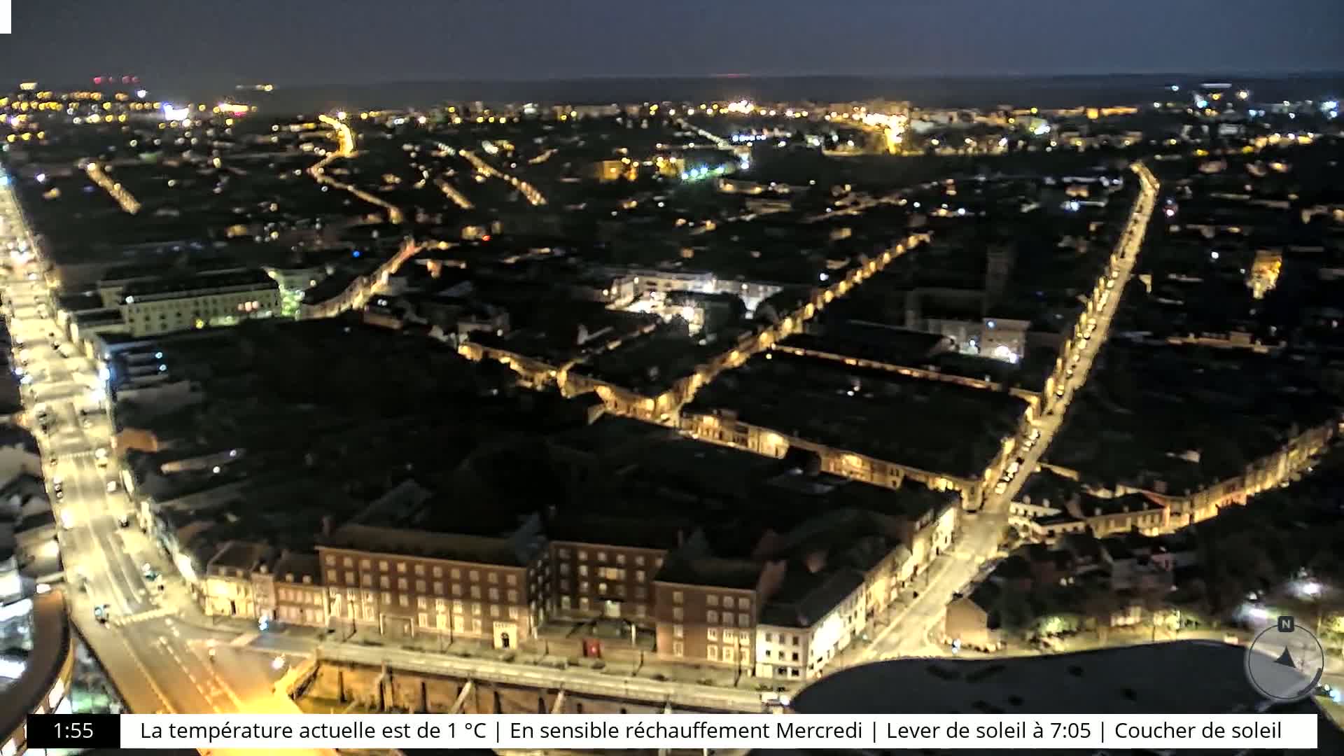 A nighttime aerial view of a city with brightly lit streets and buildings under a clear, dark sky.