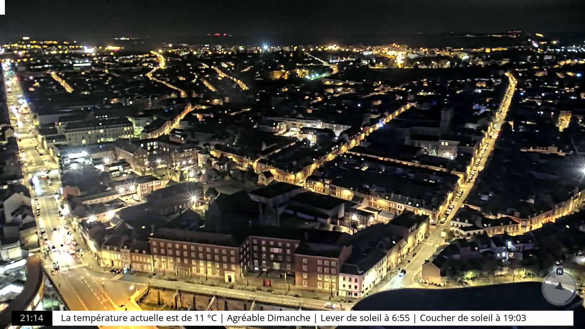 A nighttime aerial view of a city with illuminated streets and buildings.