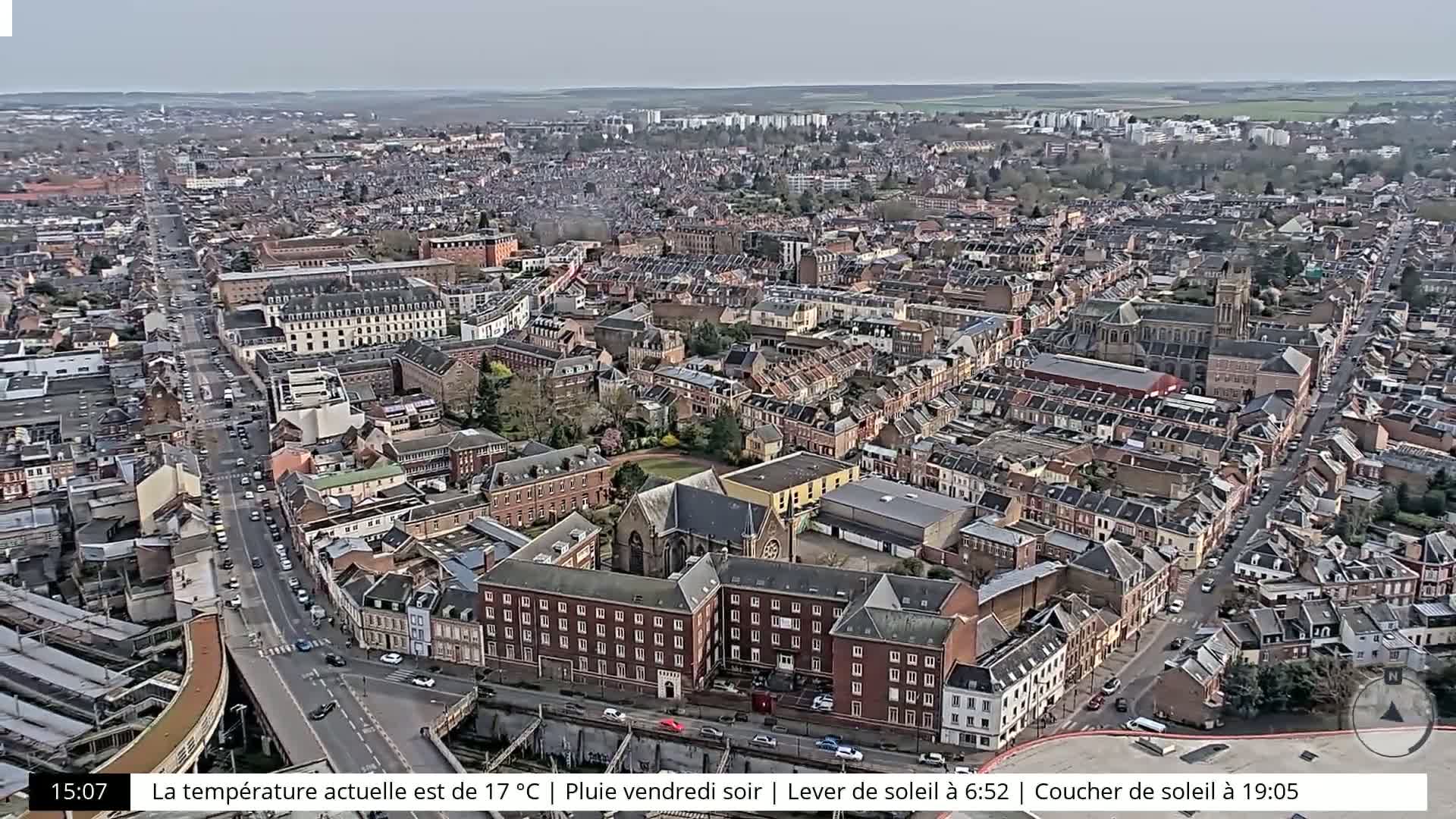 An aerial view of a densely populated city on an overcast day, showing a network of streets and buildings.
