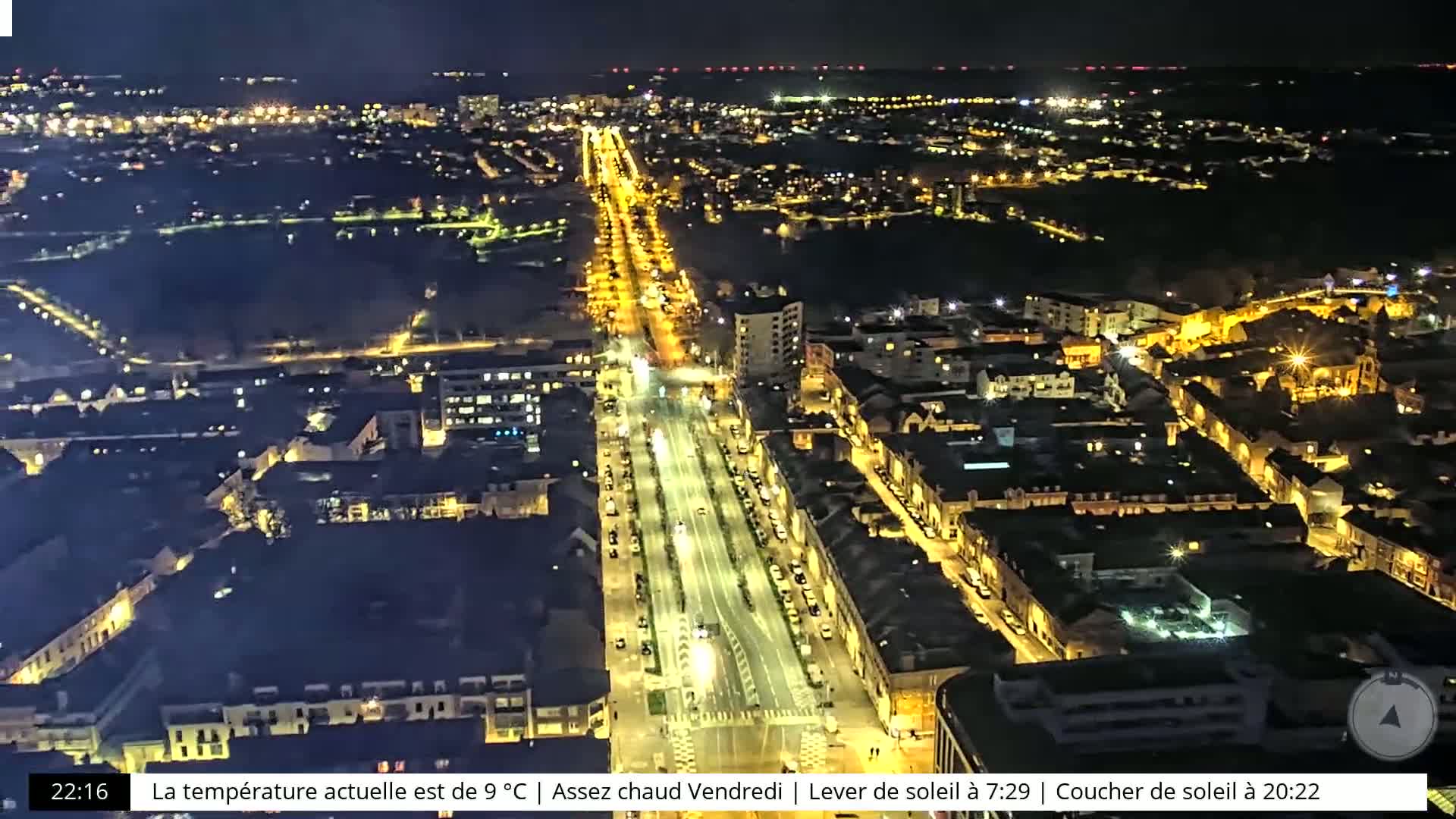 An aerial nighttime view of a city with brightly lit streets and buildings.