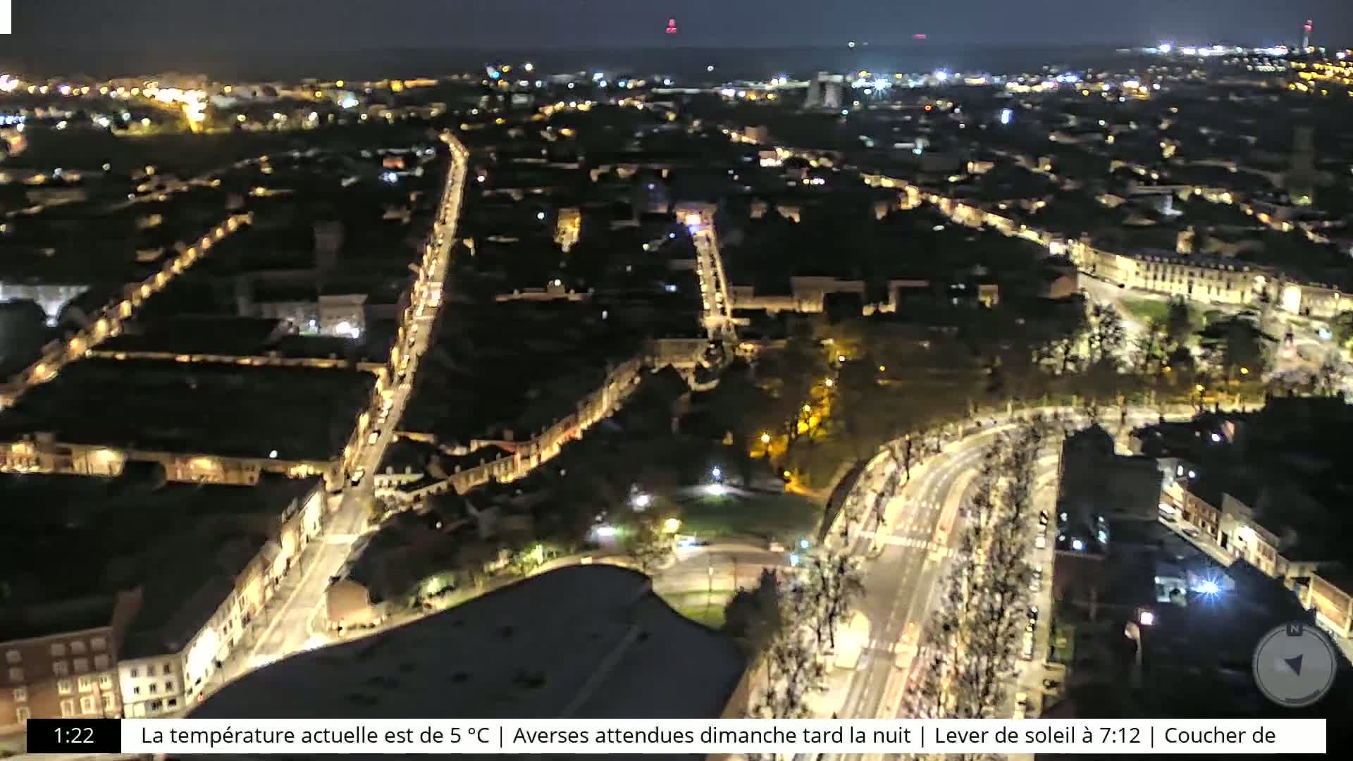 A nighttime aerial view of a city with illuminated streets and buildings, under a clear sky.