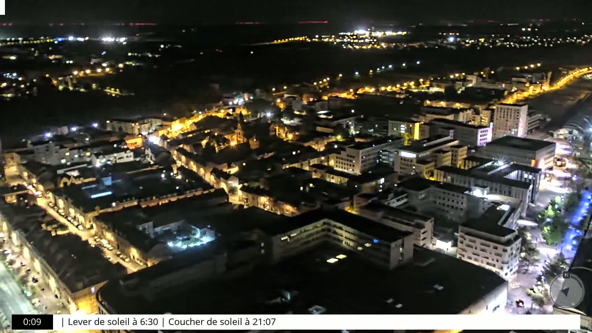 An aerial nighttime view of a city with brightly lit buildings and streets.