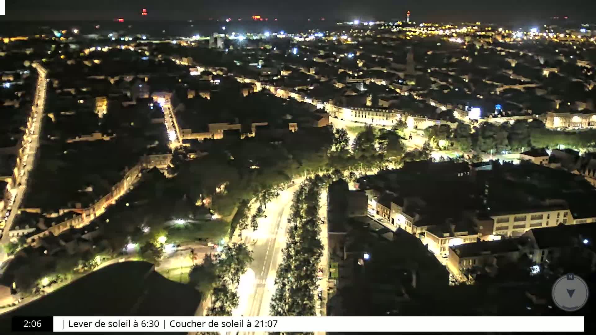 An aerial nighttime view of a city with illuminated streets and buildings under a clear sky.