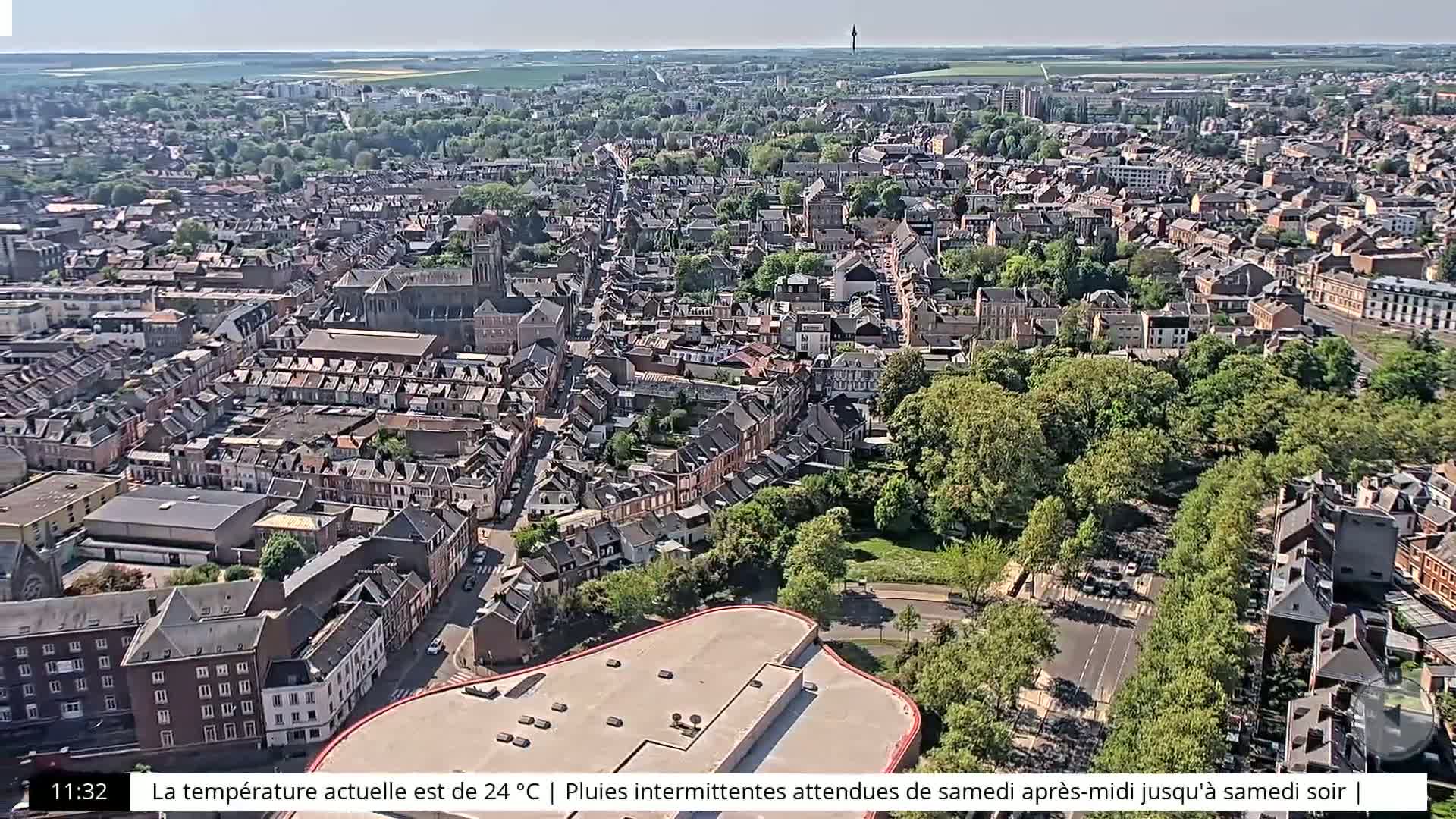 A high-angle, sunny view of a densely packed town, showing many buildings and green spaces.