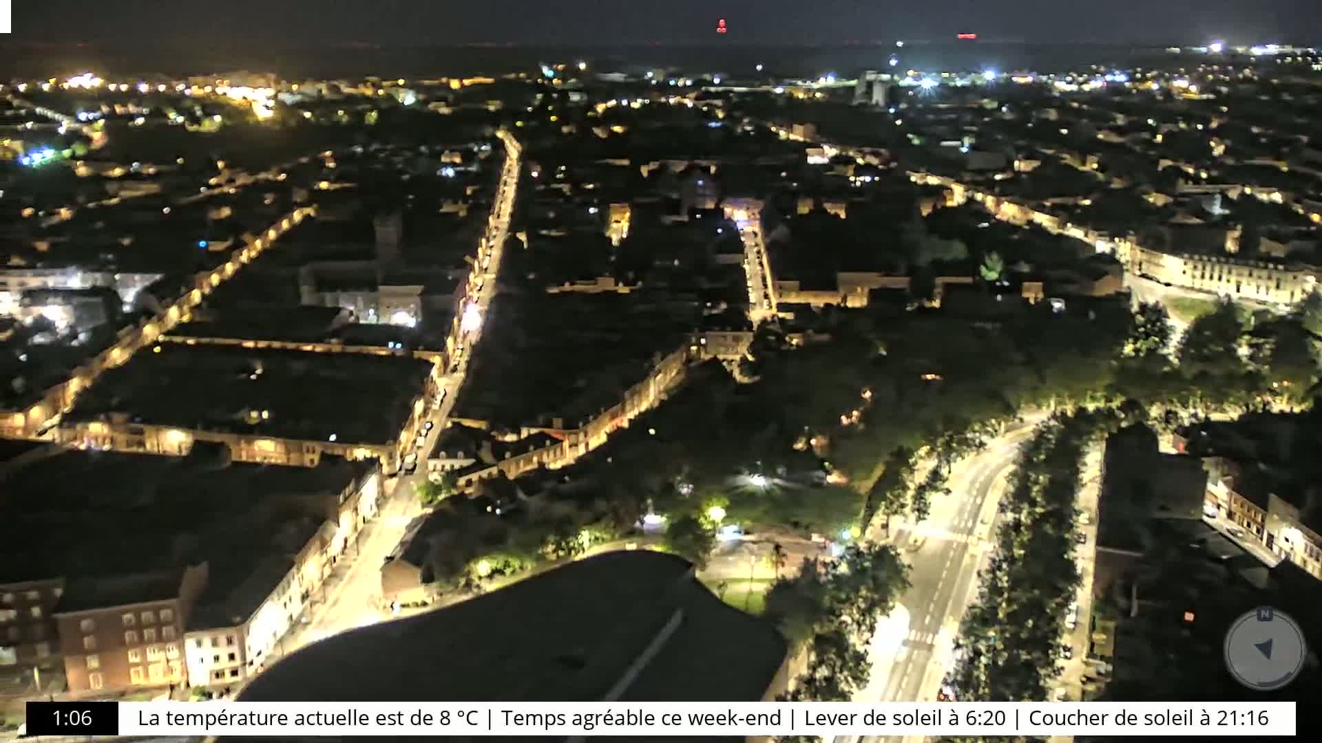 A nighttime aerial view of a city with illuminated streets and buildings, under a clear sky.