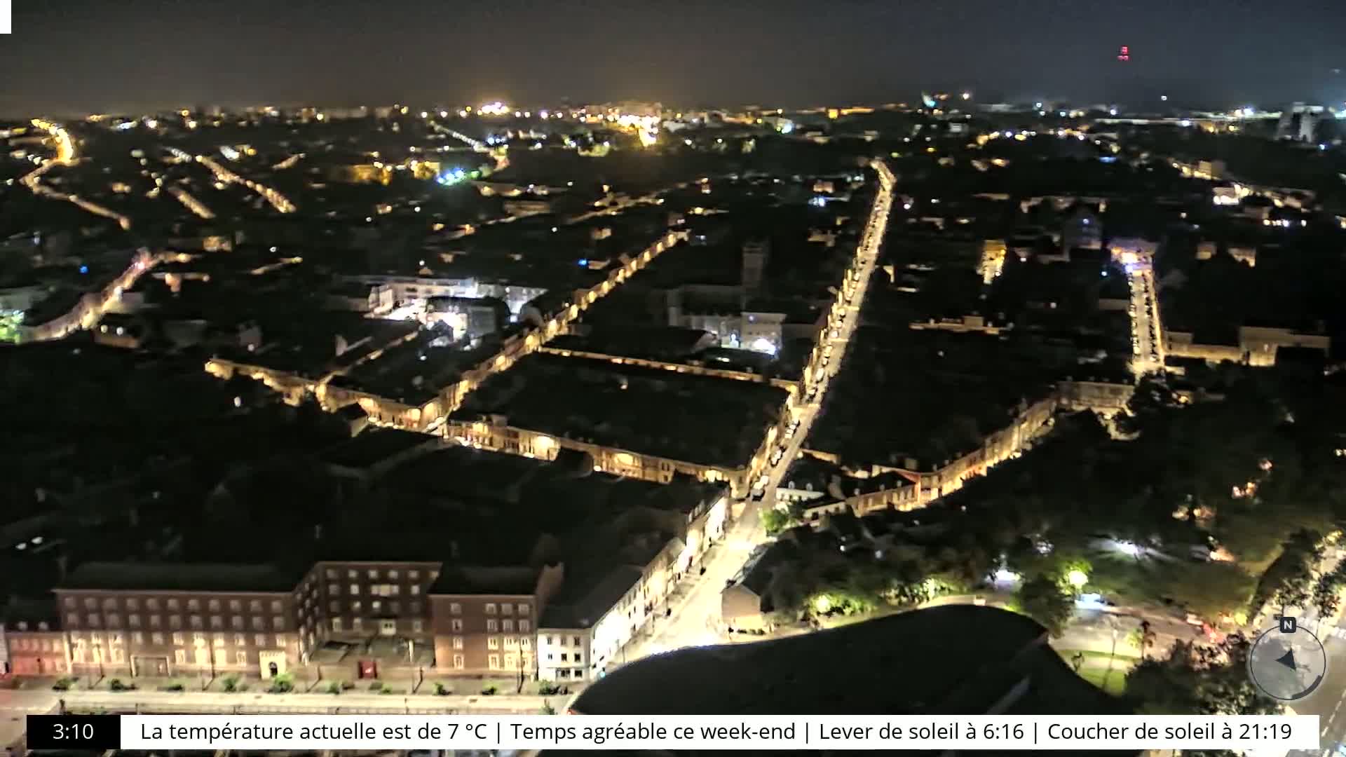 A nighttime aerial view of a city with illuminated streets and buildings.