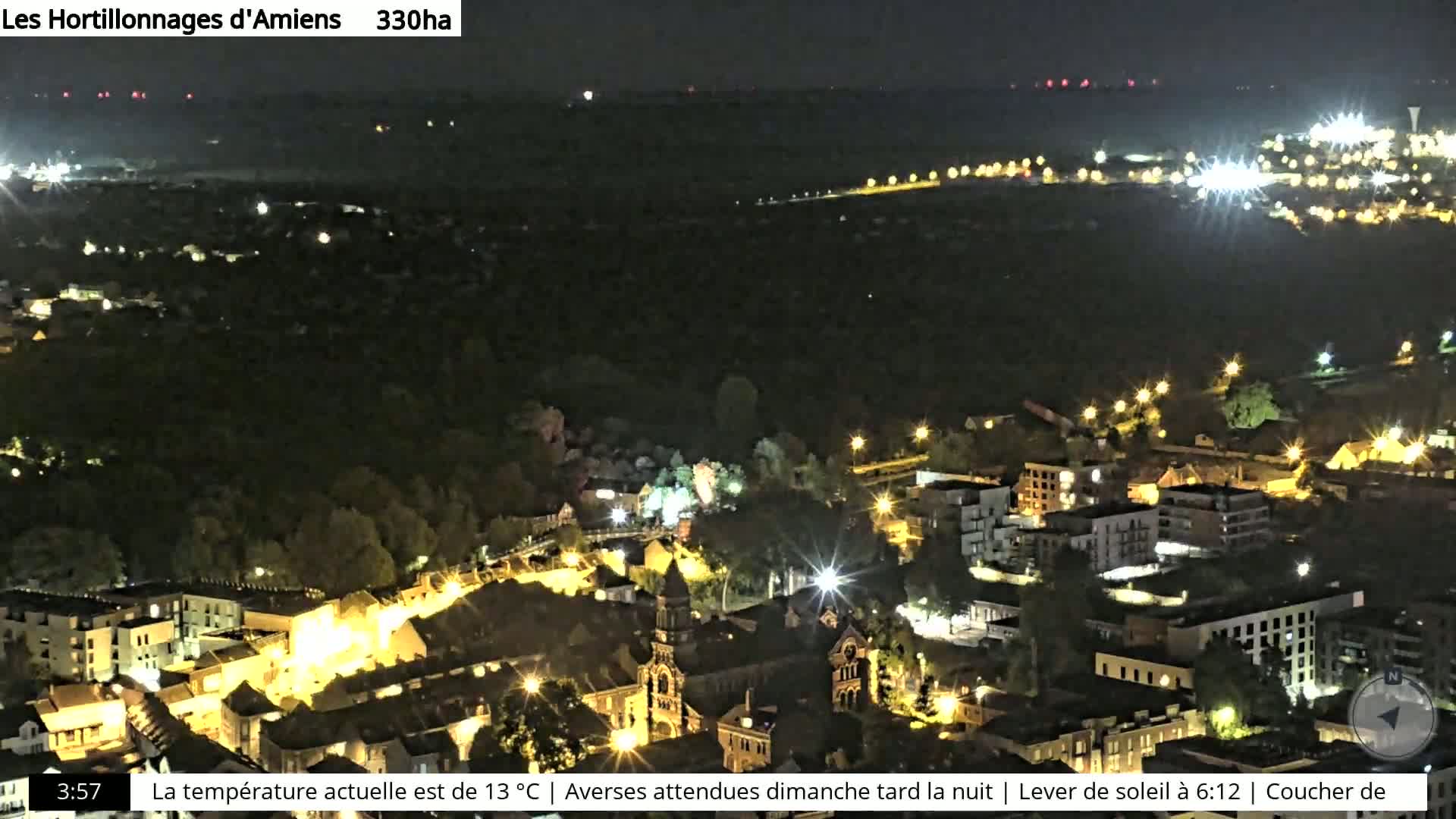 A nighttime aerial view of a town illuminated by streetlights, under a clear sky.