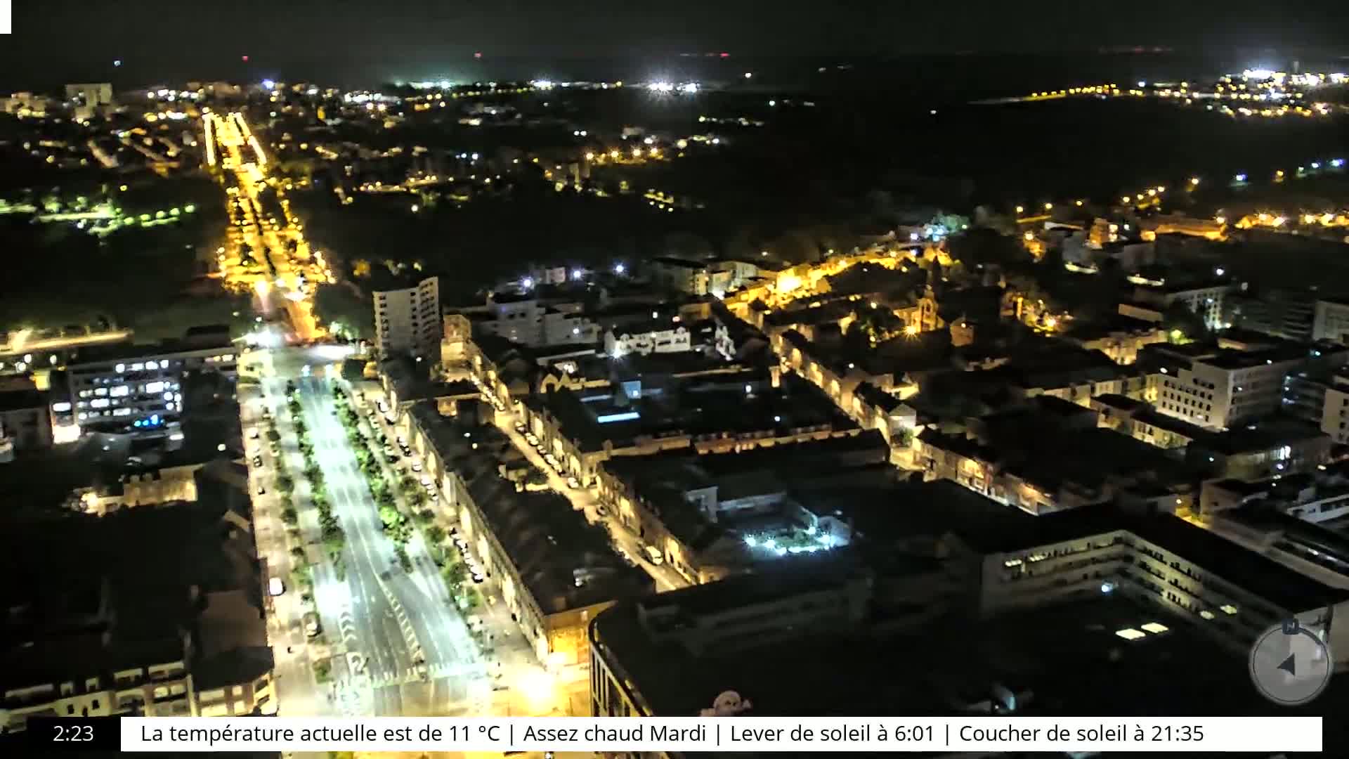 A nighttime aerial view of a city with brightly lit streets and buildings, under a clear, dark sky.