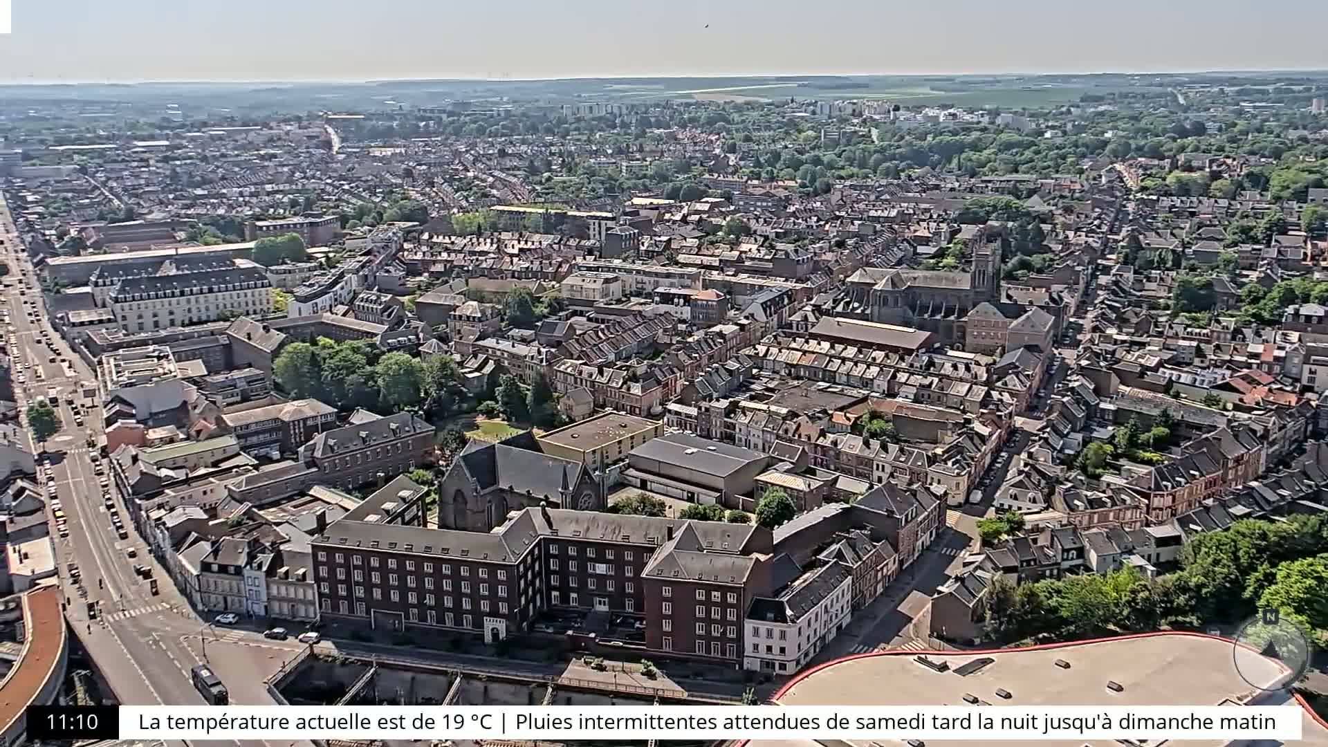 An aerial view of a densely populated city on a clear day shows numerous buildings and streets.