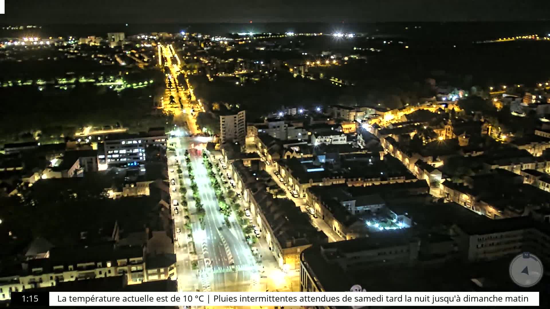 A nighttime aerial view of a city illuminated by streetlights, with surrounding dark areas suggesting parks or undeveloped land.