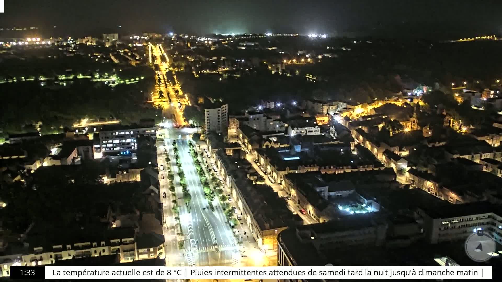 An aerial nighttime view of a city with illuminated streets and buildings, under a dark sky.