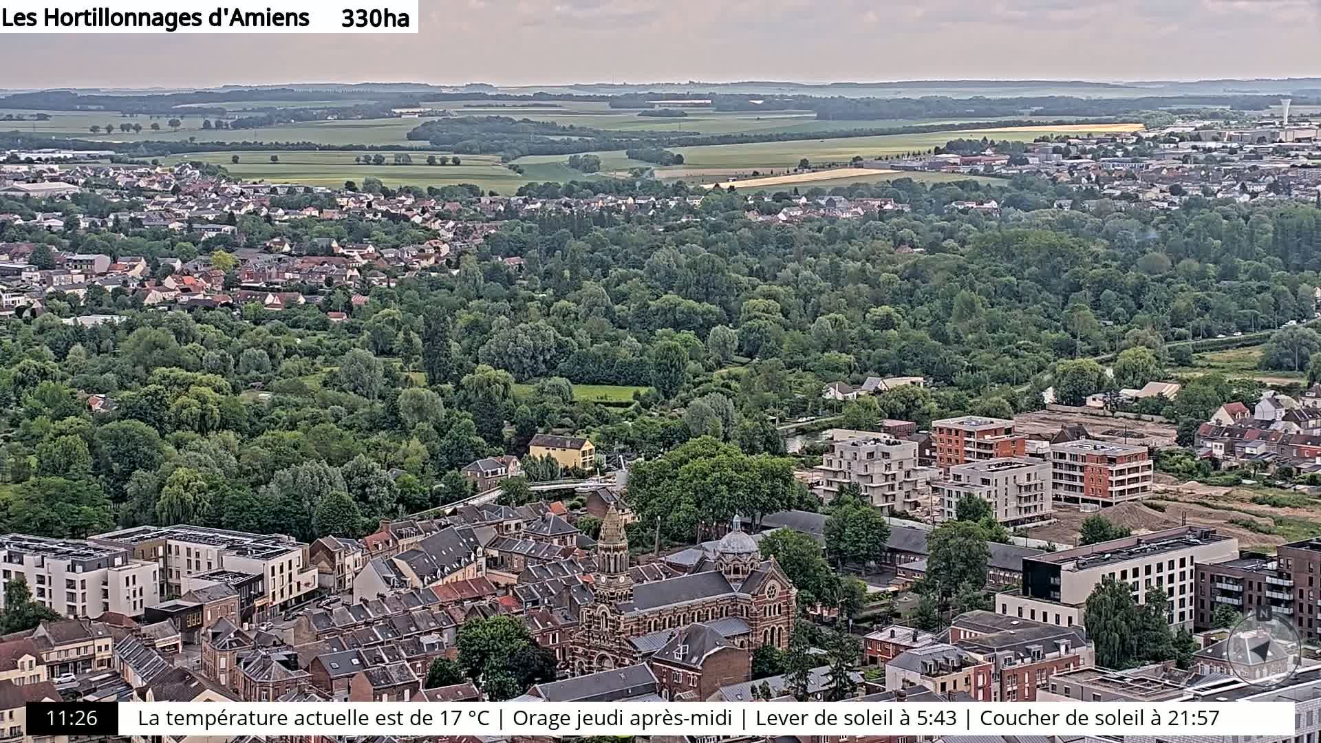 An aerial view of a town with many trees and buildings under an overcast sky.