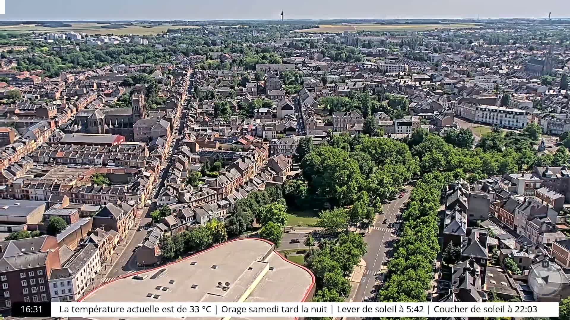 An aerial view shows a densely populated city with a large green park, under a clear sky.