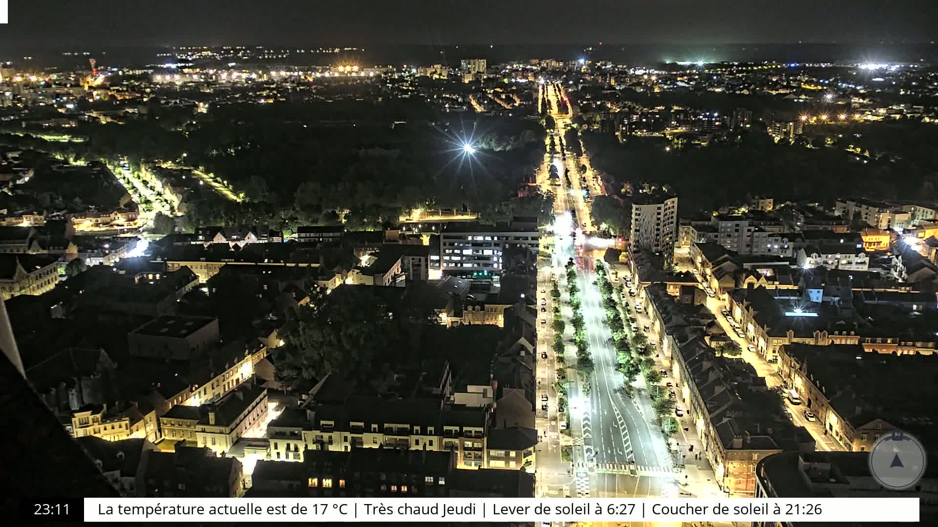 A nighttime aerial view of a city illuminated by streetlights and building lights, under a clear sky.