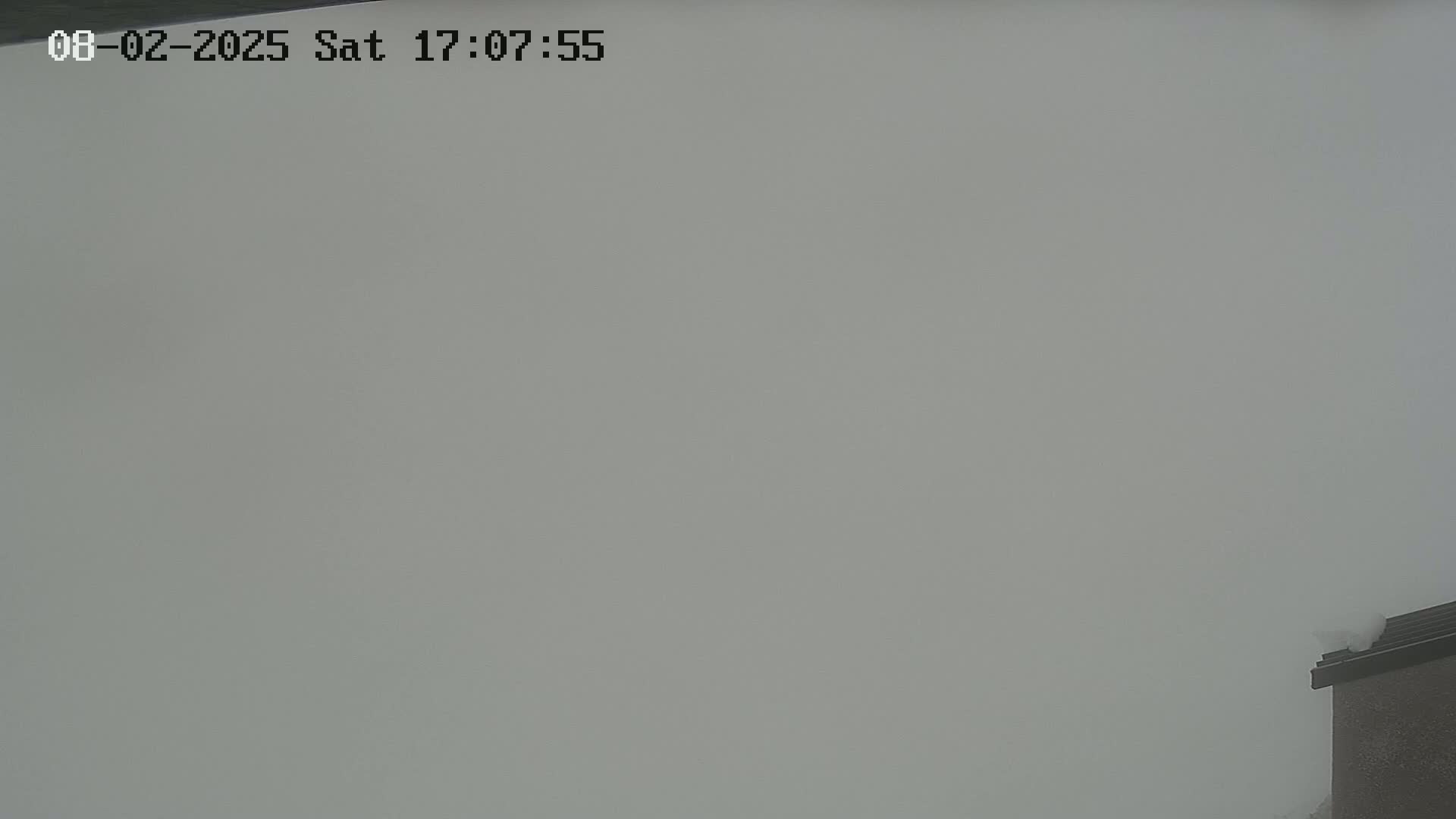 A foggy, overcast outdoor scene shows a portion of a building's roof and chimney.