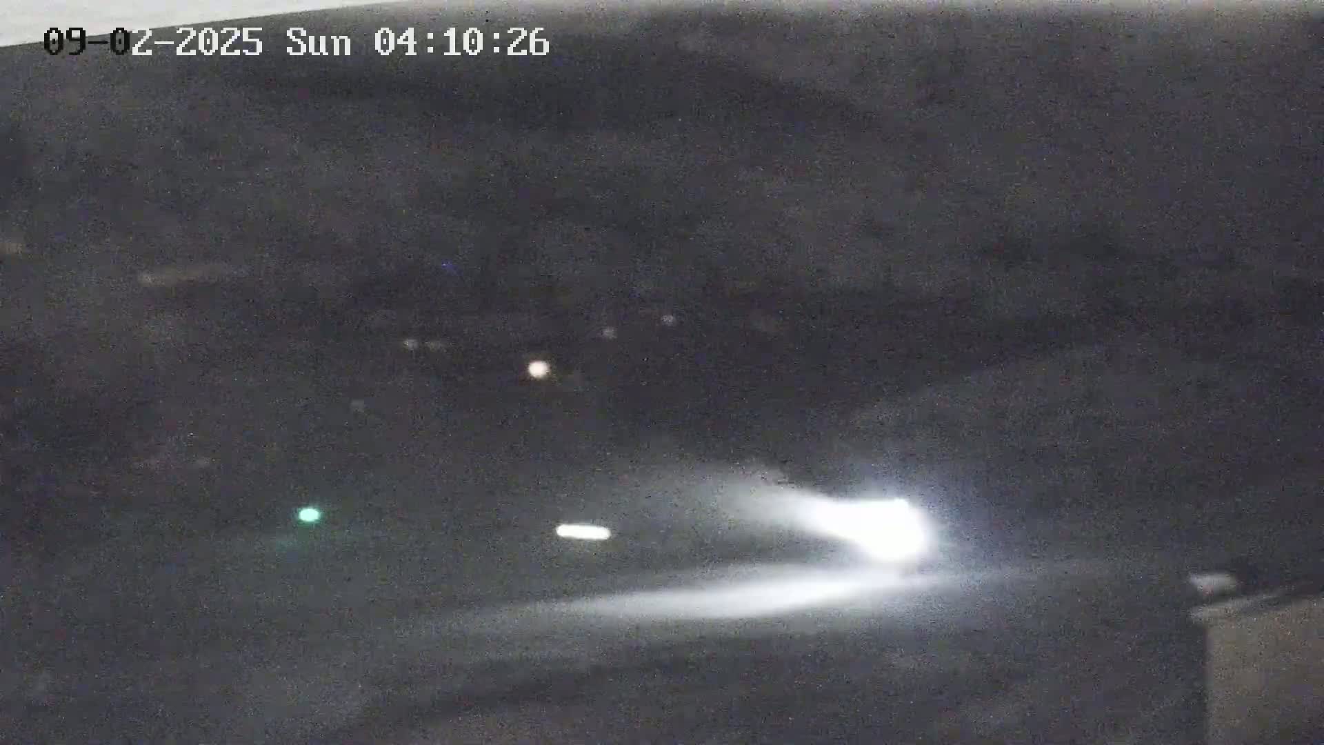 A vehicle's headlights illuminate a dark, nighttime road.