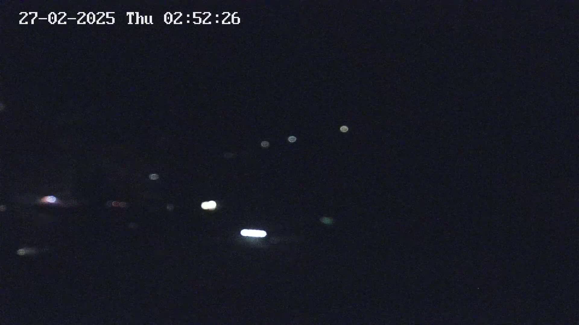 A nighttime, low-light image shows several blurry lights in the distance.