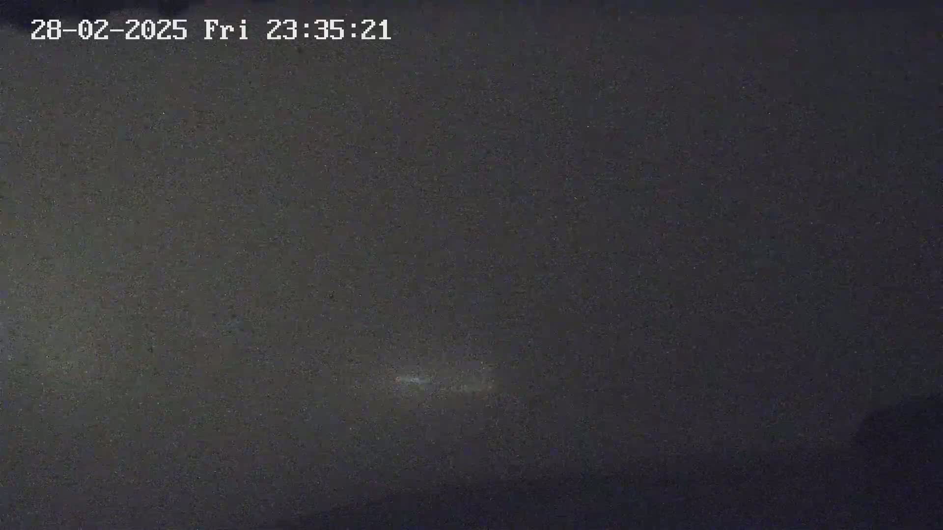 A dark, nighttime scene shows a faint, horizontal streak of light in the distance.