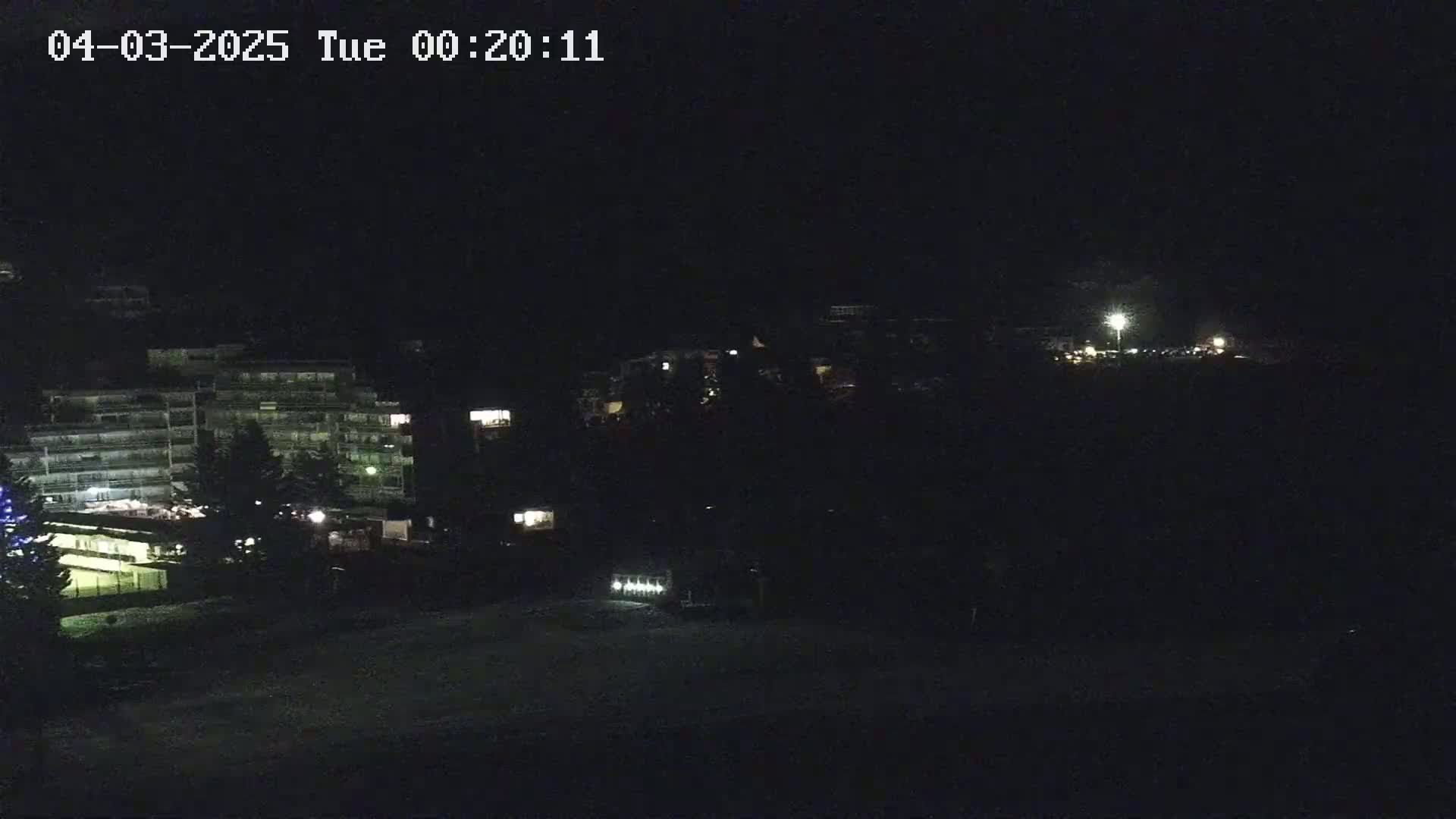 A nighttime, dimly lit view of buildings and a snow-covered area.
