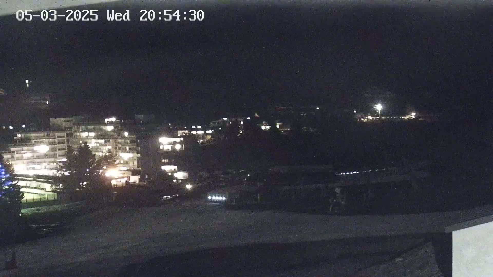 A nighttime view of illuminated buildings and a snow-covered area.