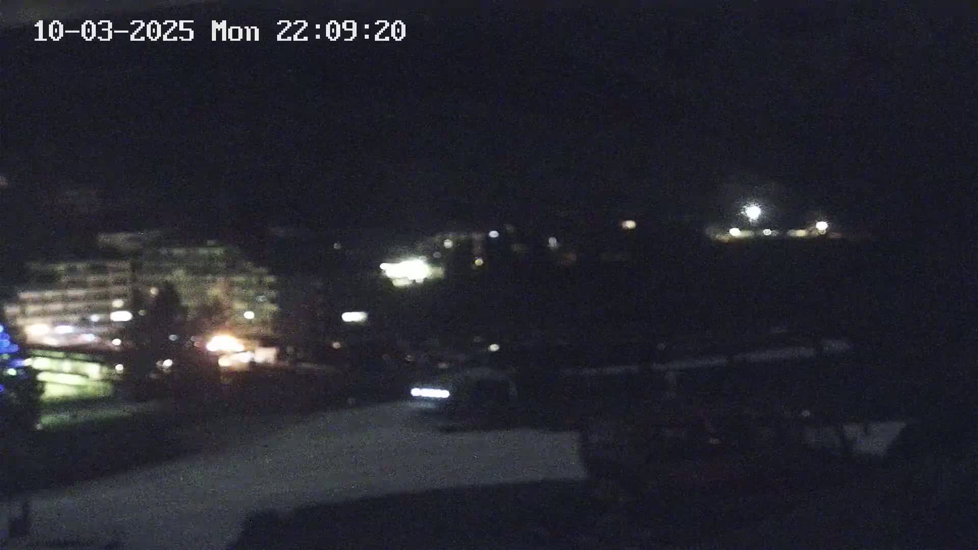 A nighttime, blurry view of a snow-covered area with distant building lights.