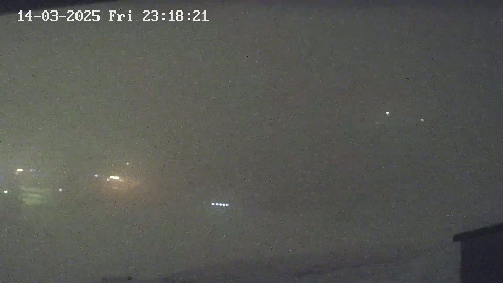 A hazy night scene shows distant headlights and a few faint lights in the sky.