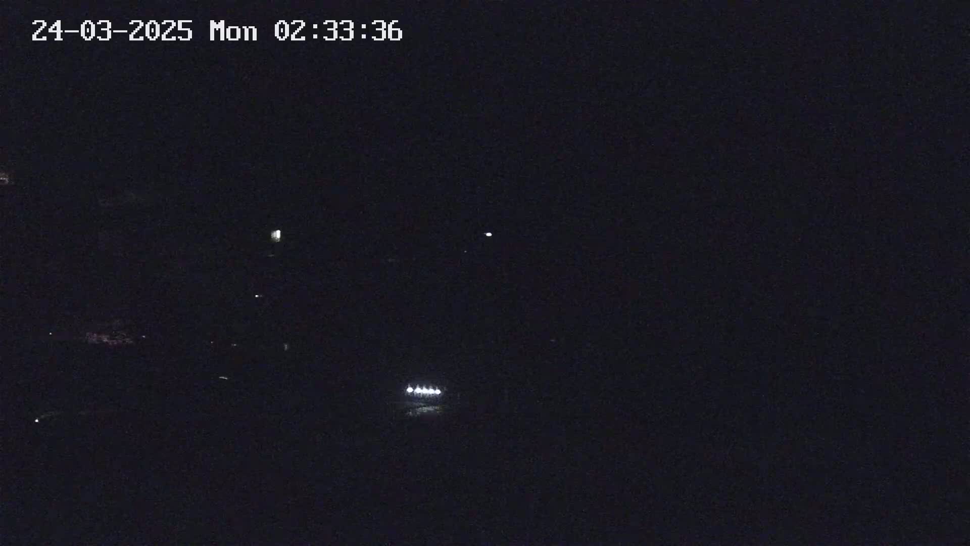 A nighttime, low-light view shows a few faint lights in the distance.