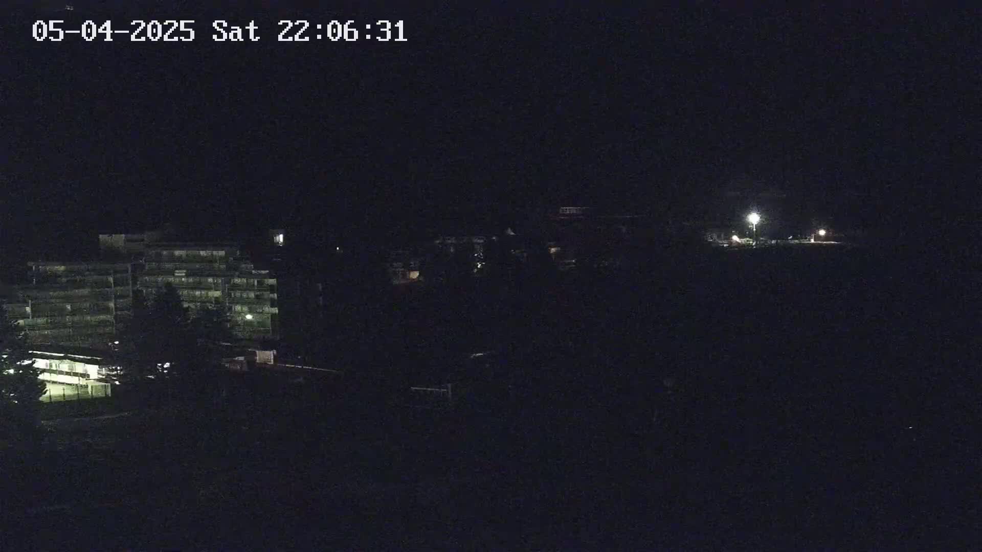 A nighttime view of a multi-story building and other structures illuminated by dim lighting.