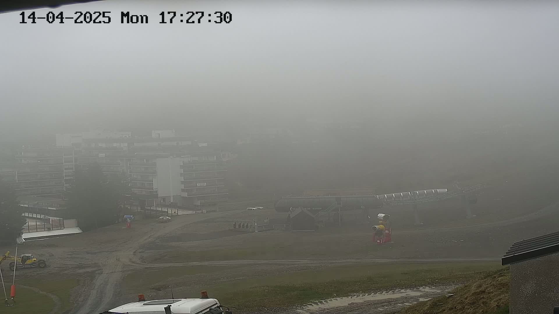 A foggy view of a building complex and what appears to be a ski lift, partially obscured by thick fog.