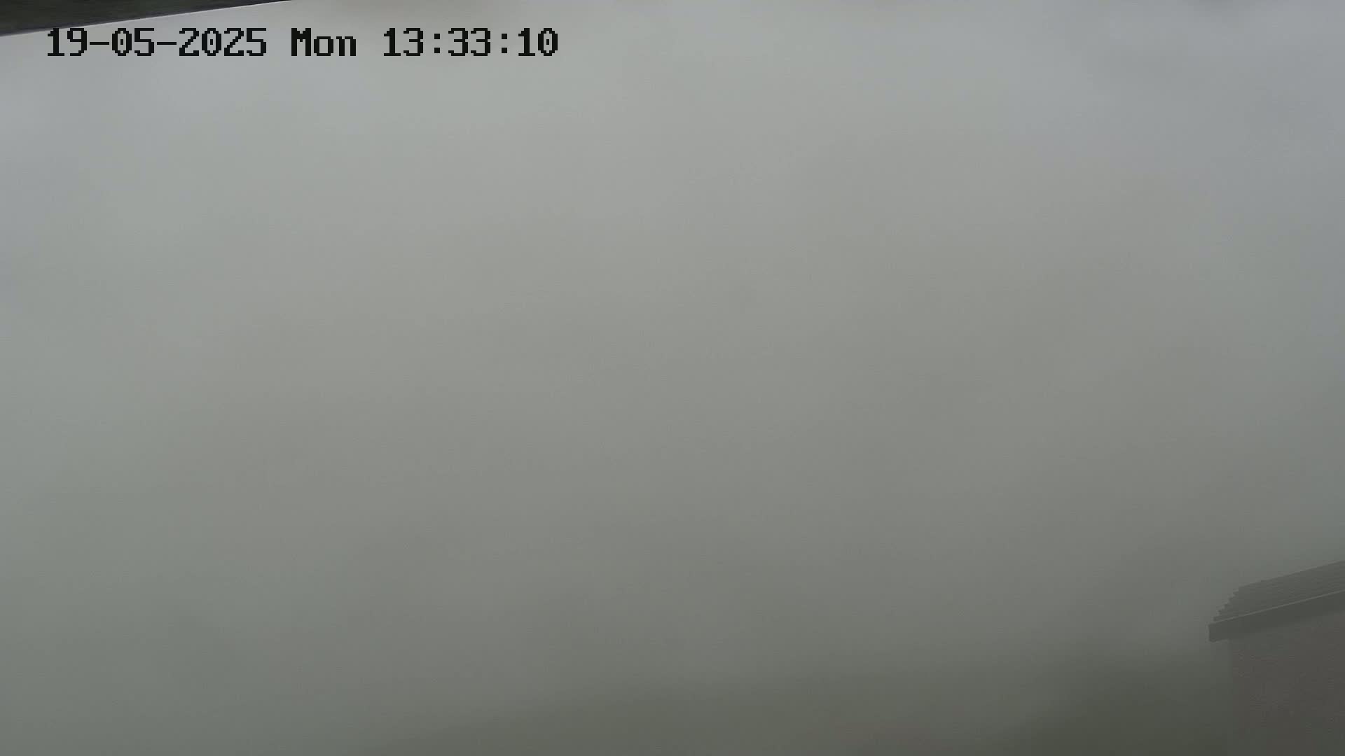 A corner of a building is barely visible through a thick fog.
