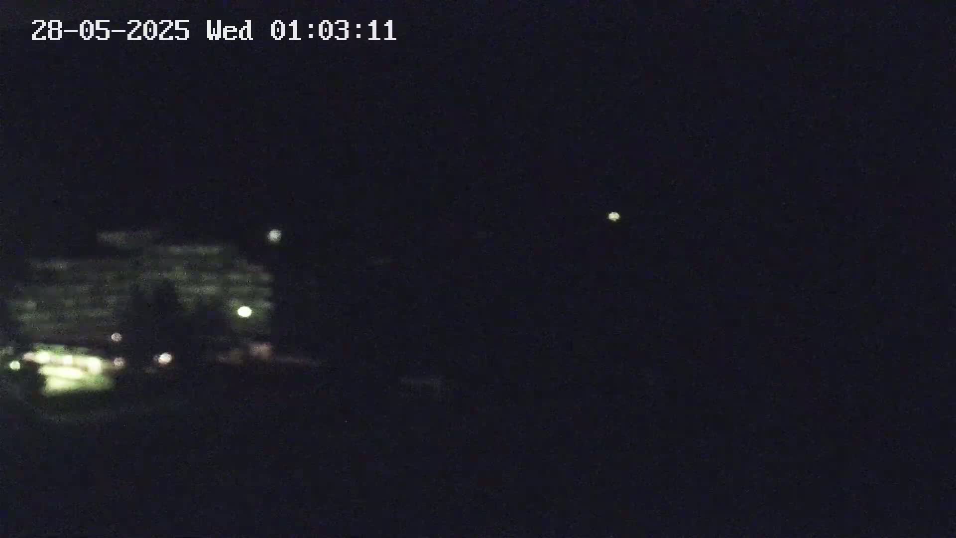 A dimly lit building is visible in the distance under a dark night sky.