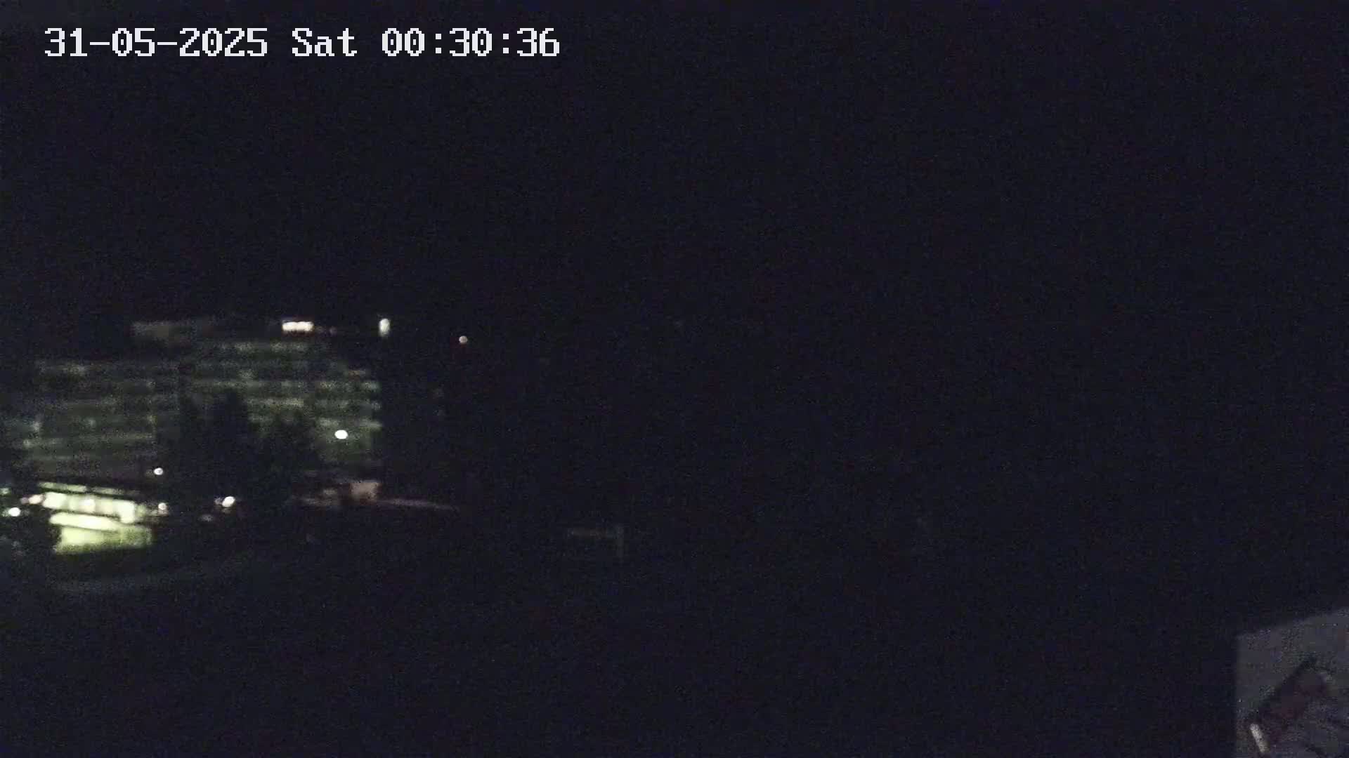 A dimly lit building is visible at night, surrounded by darkness.