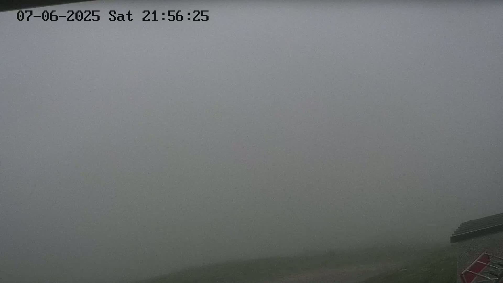 A foggy, outdoor scene shows a small portion of a building in the bottom right corner.