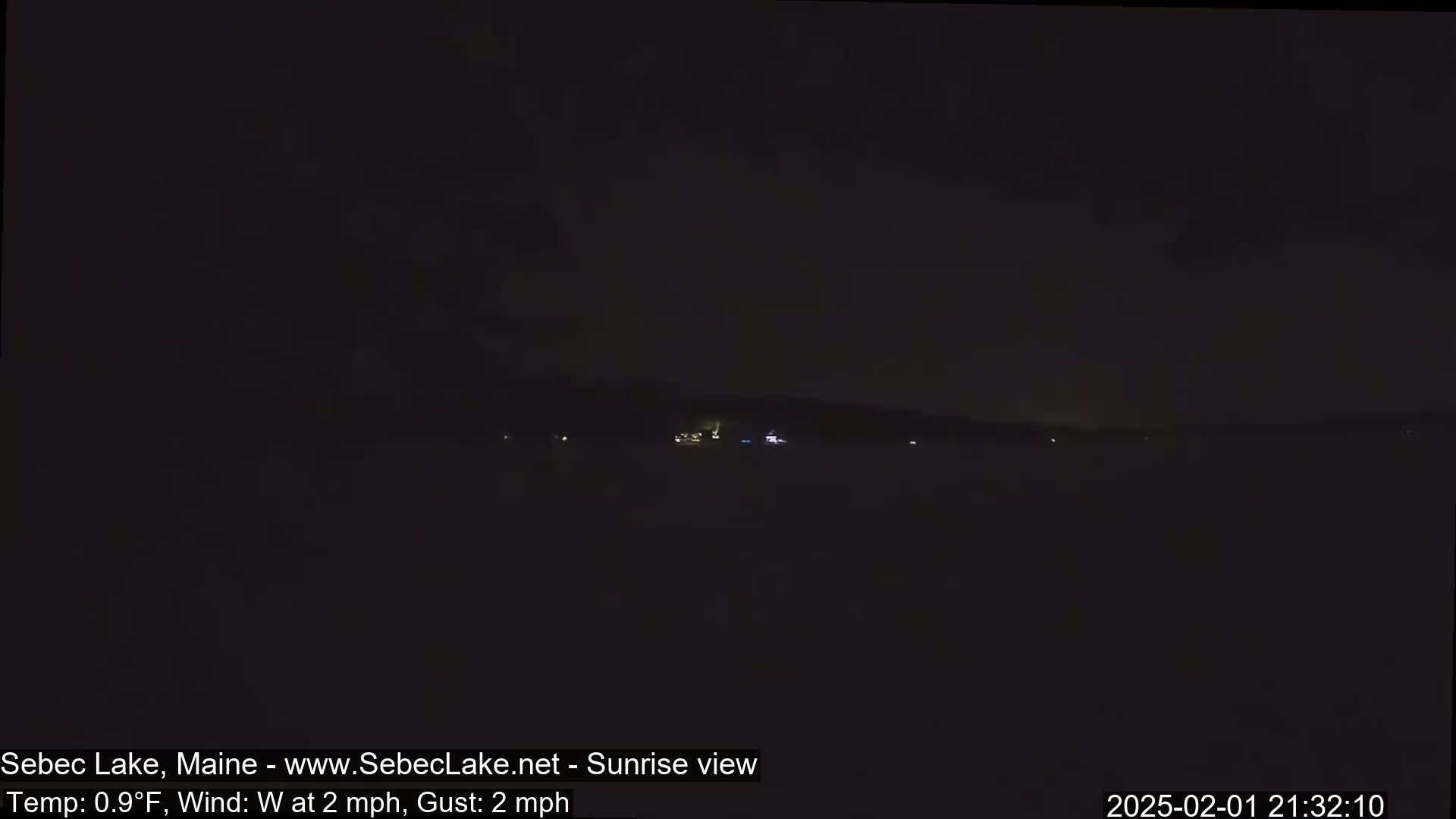 A nighttime long shot shows a dark body of water with faintly visible lights on the far shore under a dark sky.