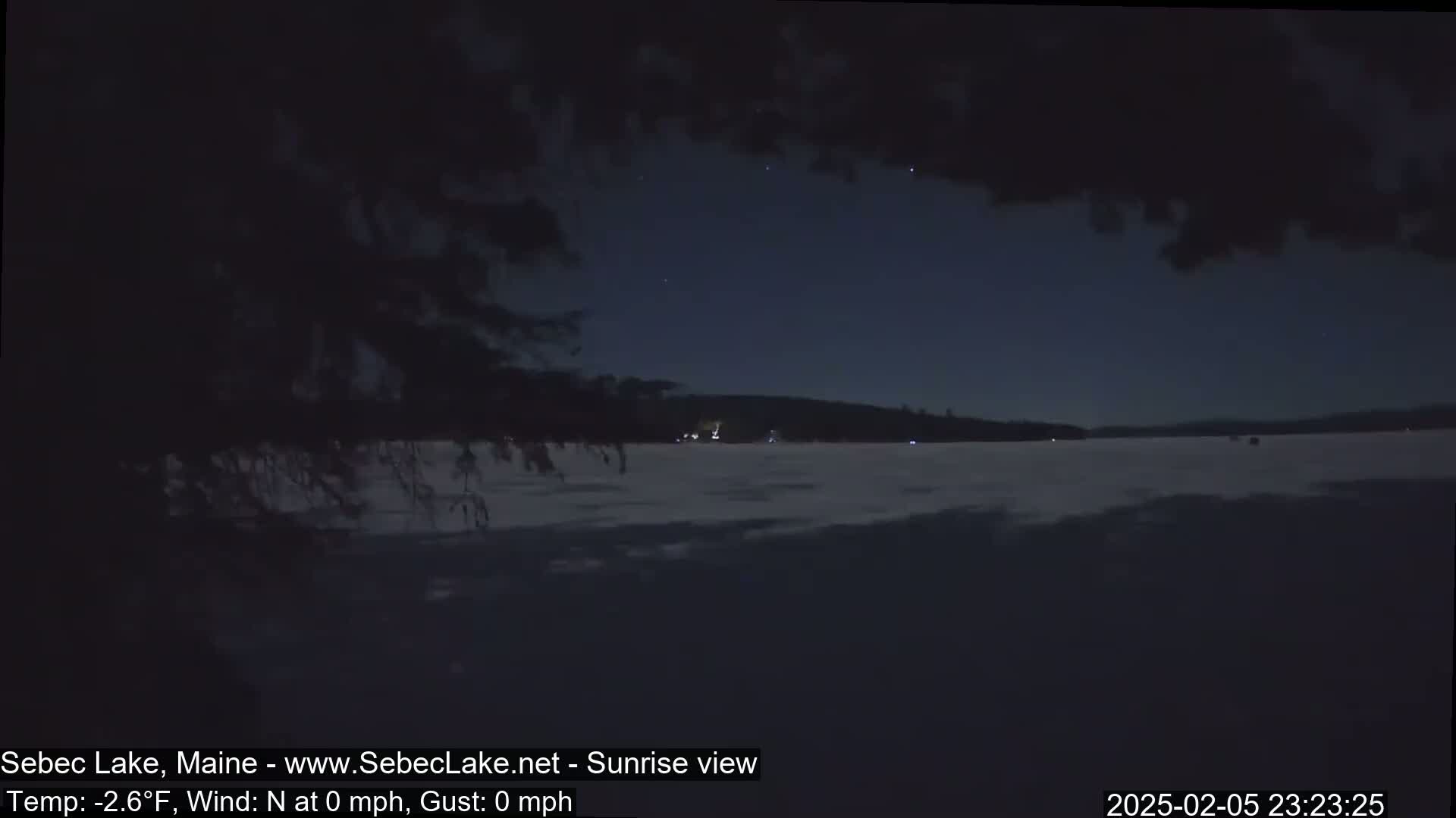 A frozen lake is visible under a dark night sky with a few stars;  the temperature is -2.6°F and there is no wind.