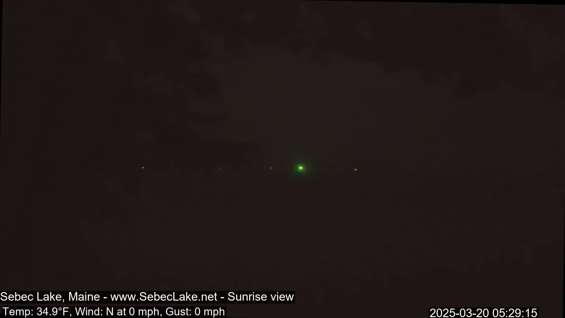 A dark, nighttime scene shows a few distant lights and a dark, possibly cloudy sky.
