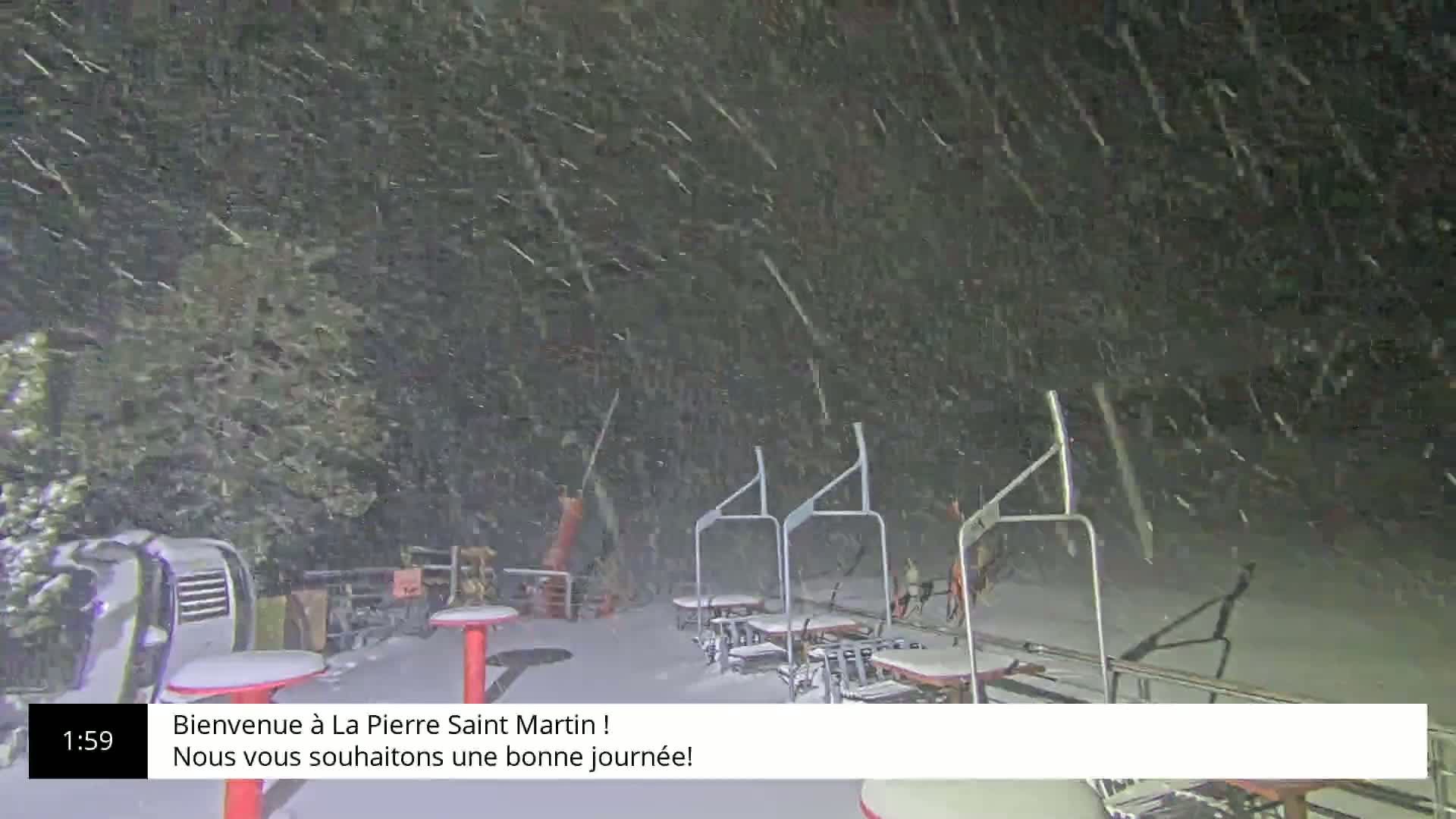 A snow-covered ski lift area is heavily blanketed in falling snow at night.