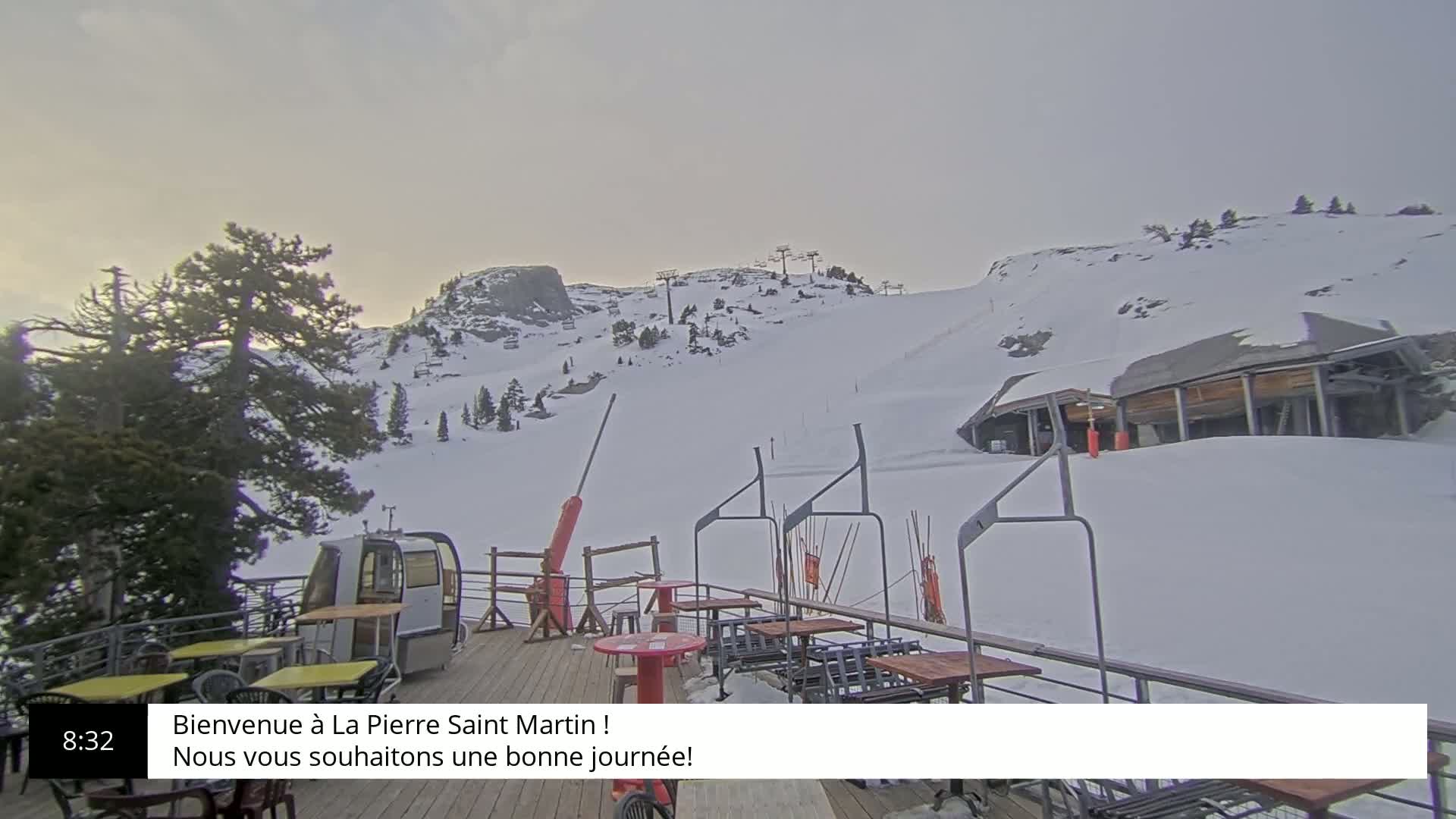 A snowy mountain slope with ski lifts and a deck with outdoor seating is visible under an overcast sky.