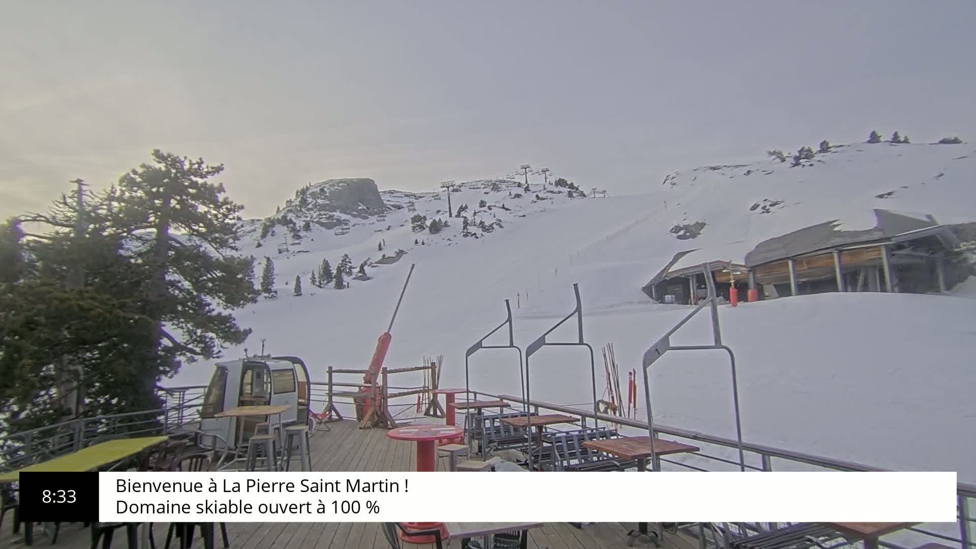 A snow-covered ski slope with a chairlift and outdoor seating area is visible under an overcast sky.