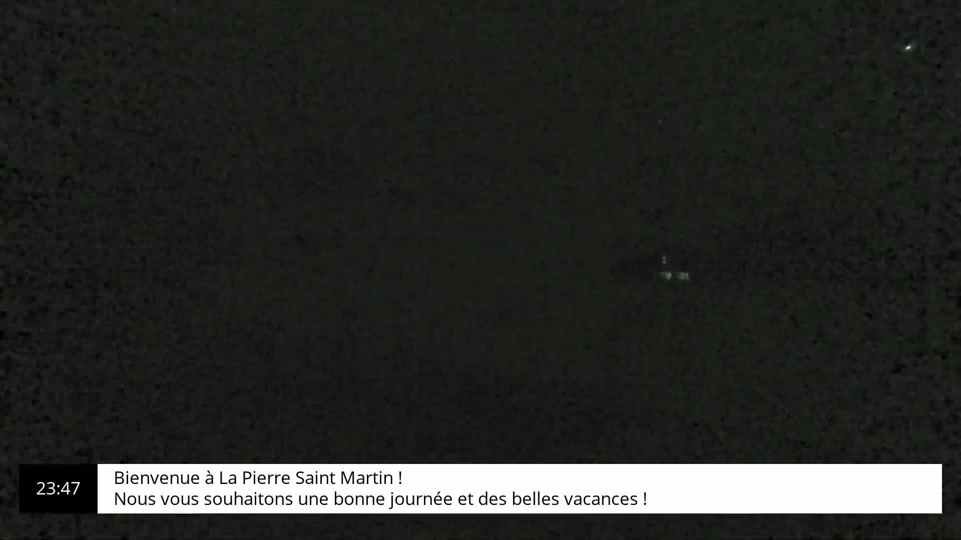 A dark, grainy image shows a mostly black background with a few very faint, lighter specks.