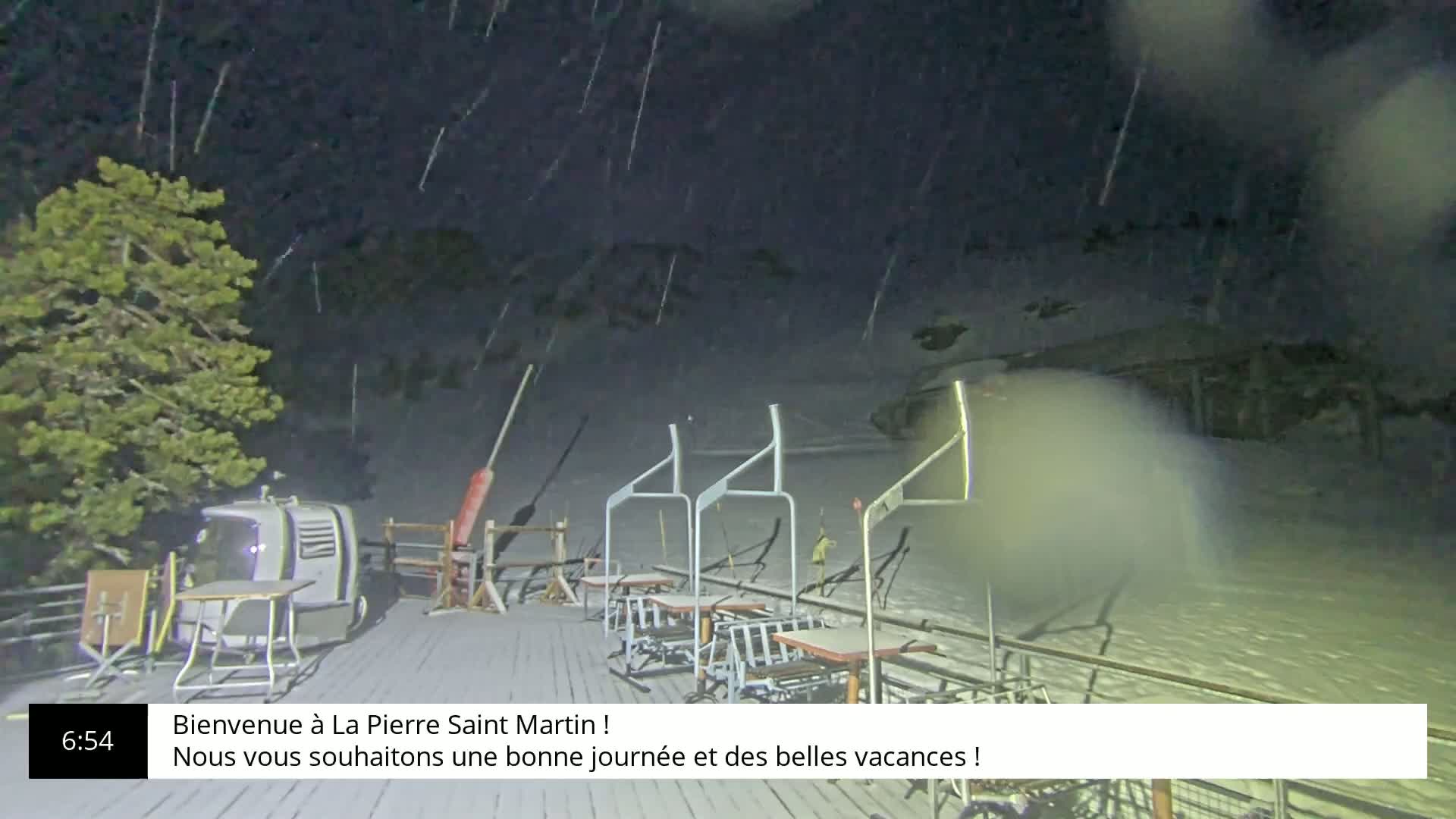A ski lift base is covered in snow during a nighttime snowfall.