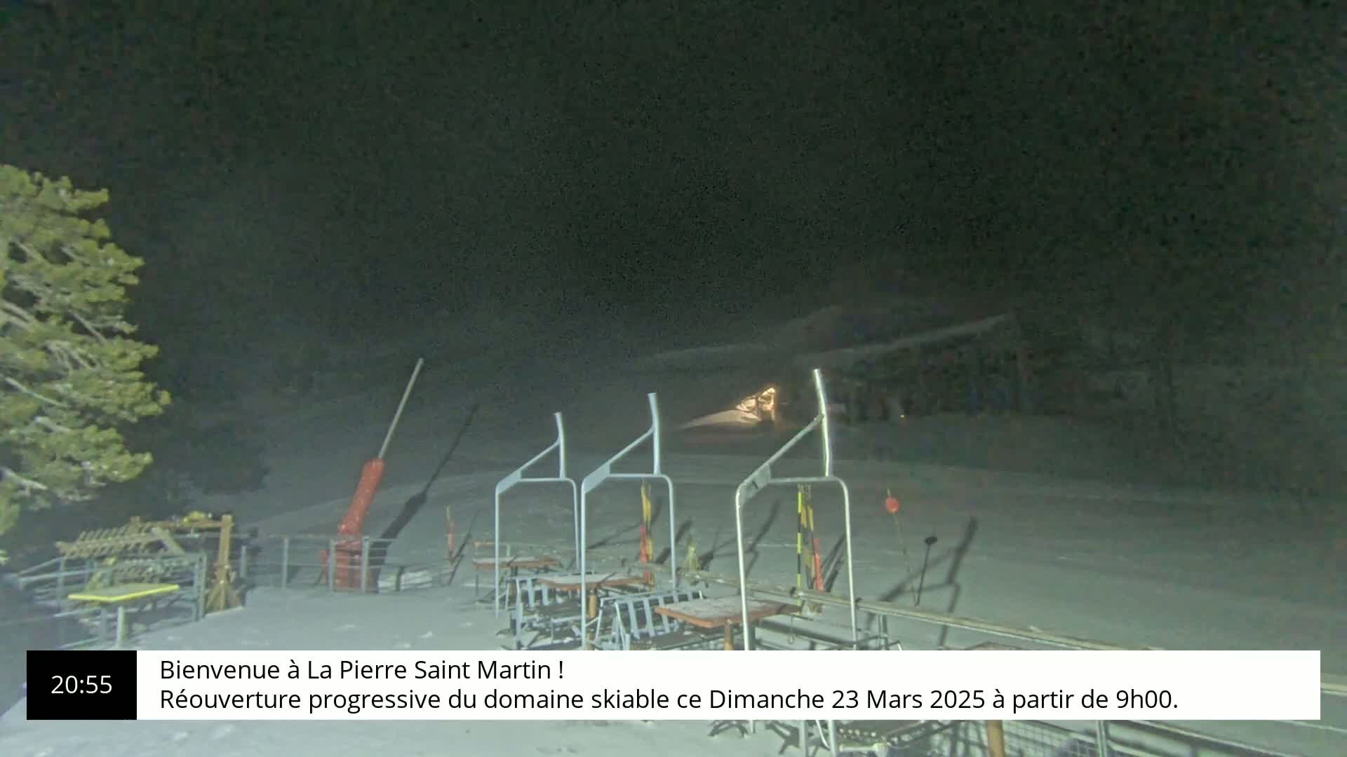 A nighttime view of a snow-covered ski lift with several empty chairs under a dark sky.