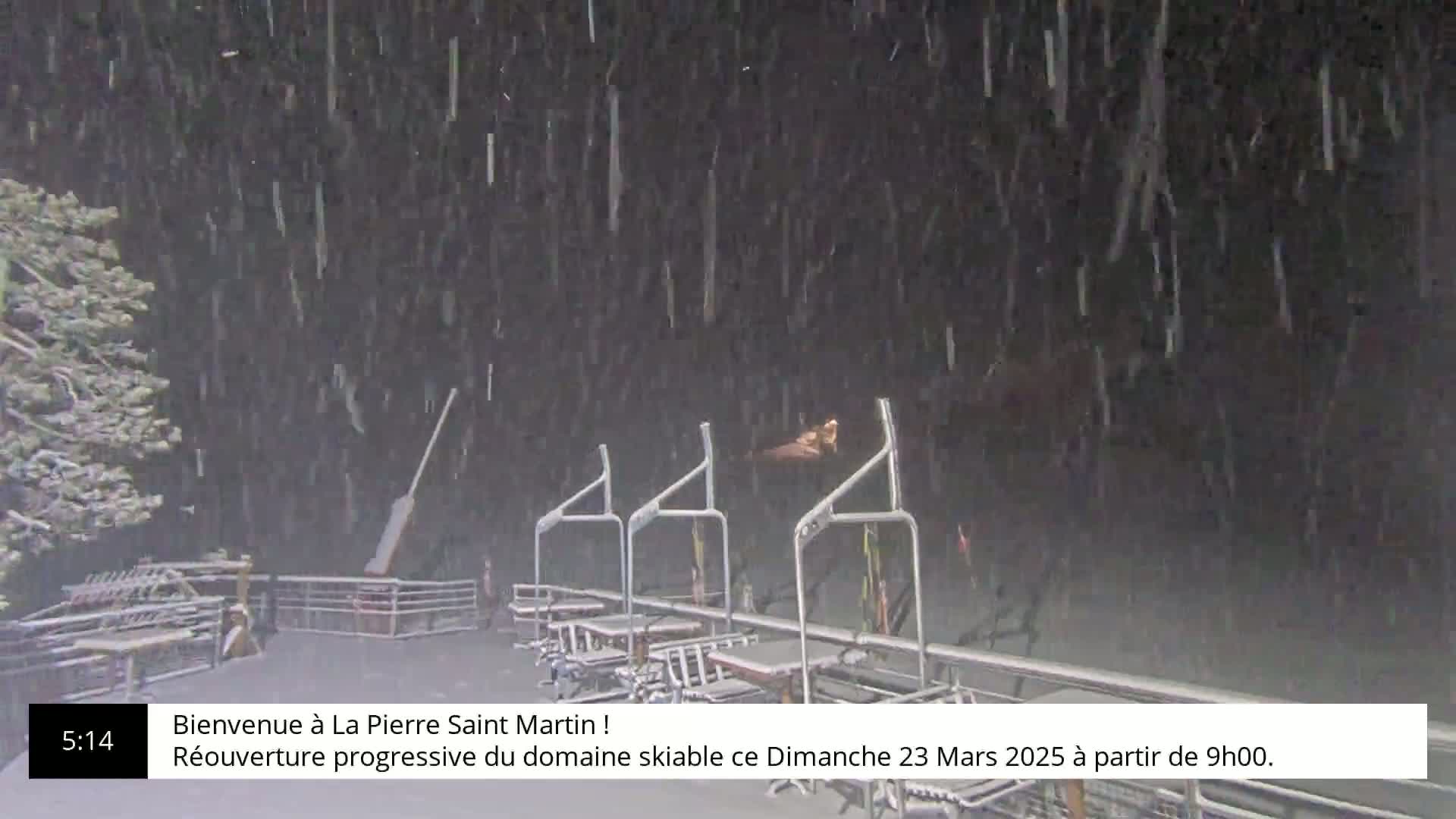 Empty ski lift chairs sit under heavy snowfall at night.