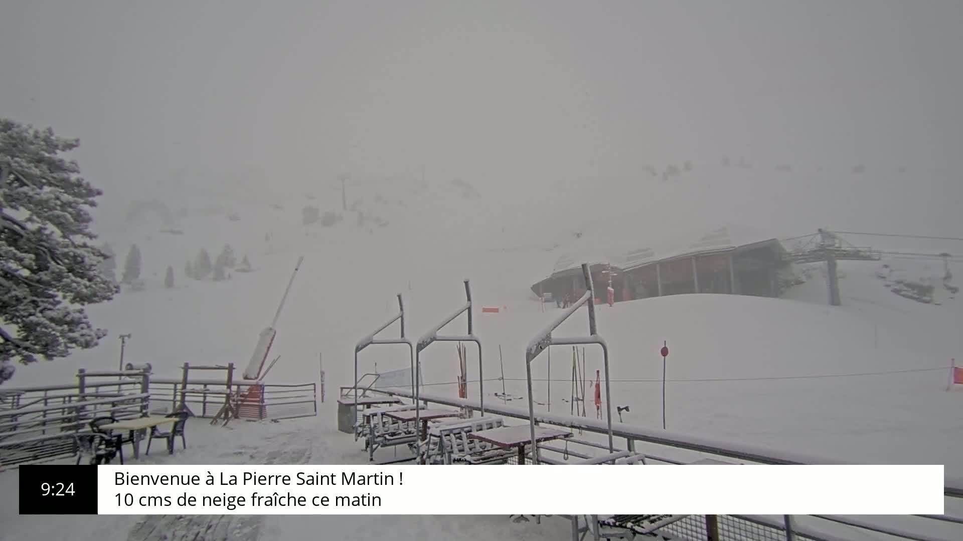 A snow-covered ski resort is seen on a heavily overcast day with falling snow.