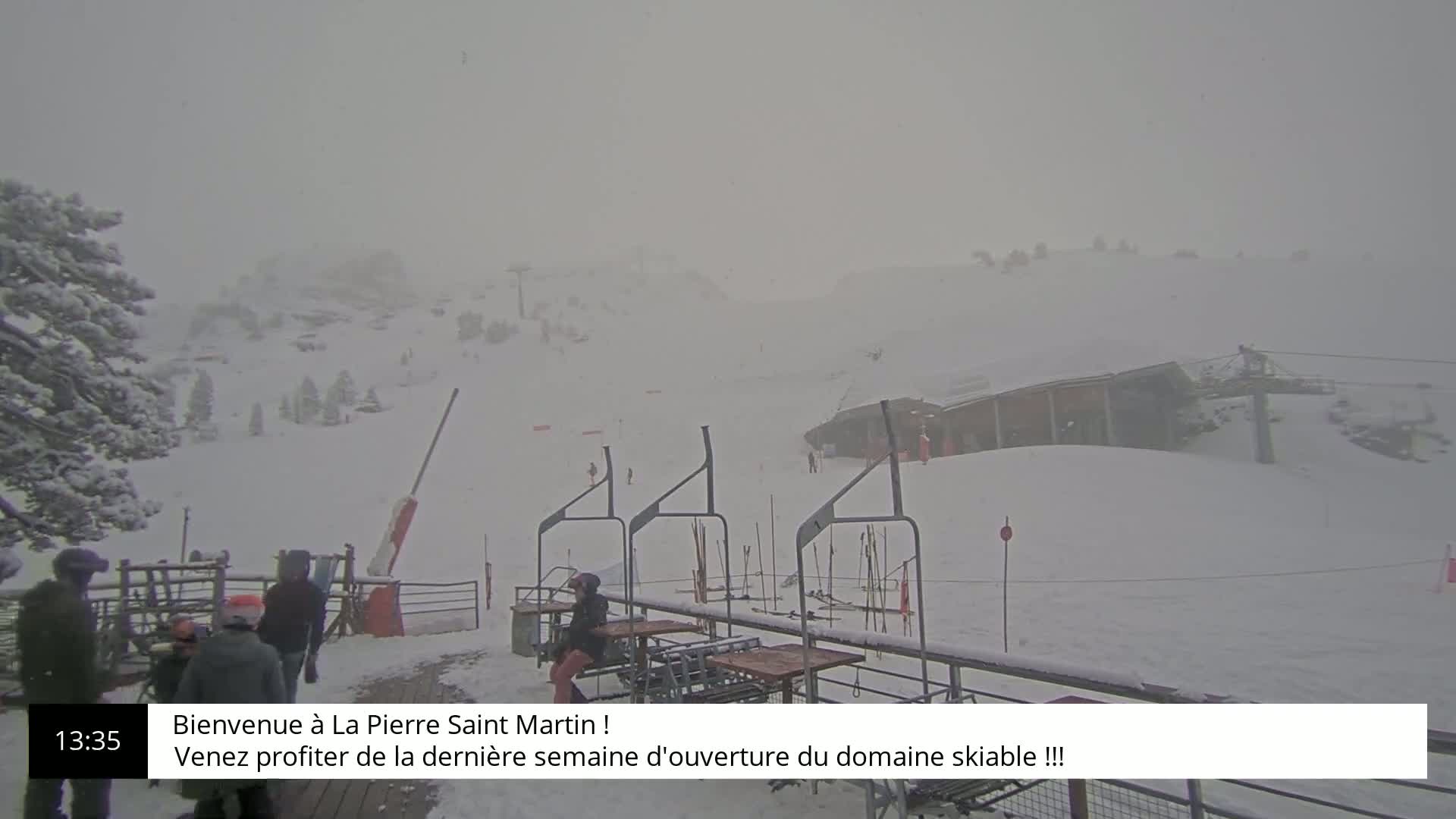 A snowy ski resort scene is visible through heavy snowfall, showing a chairlift and several people bundled in winter clothing.