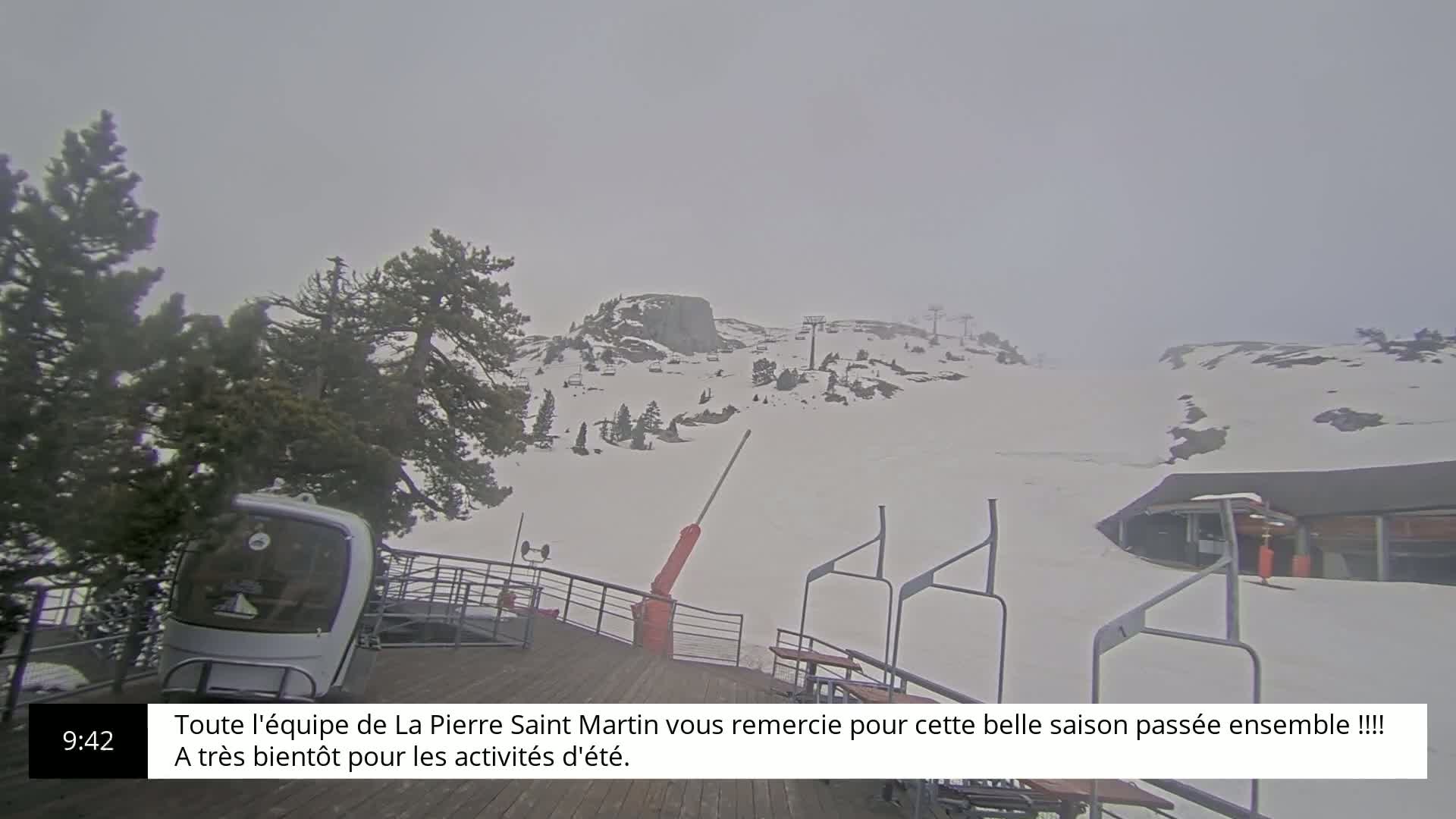 A snow-covered ski slope is visible on an overcast day, with a chairlift and a small building in the background.